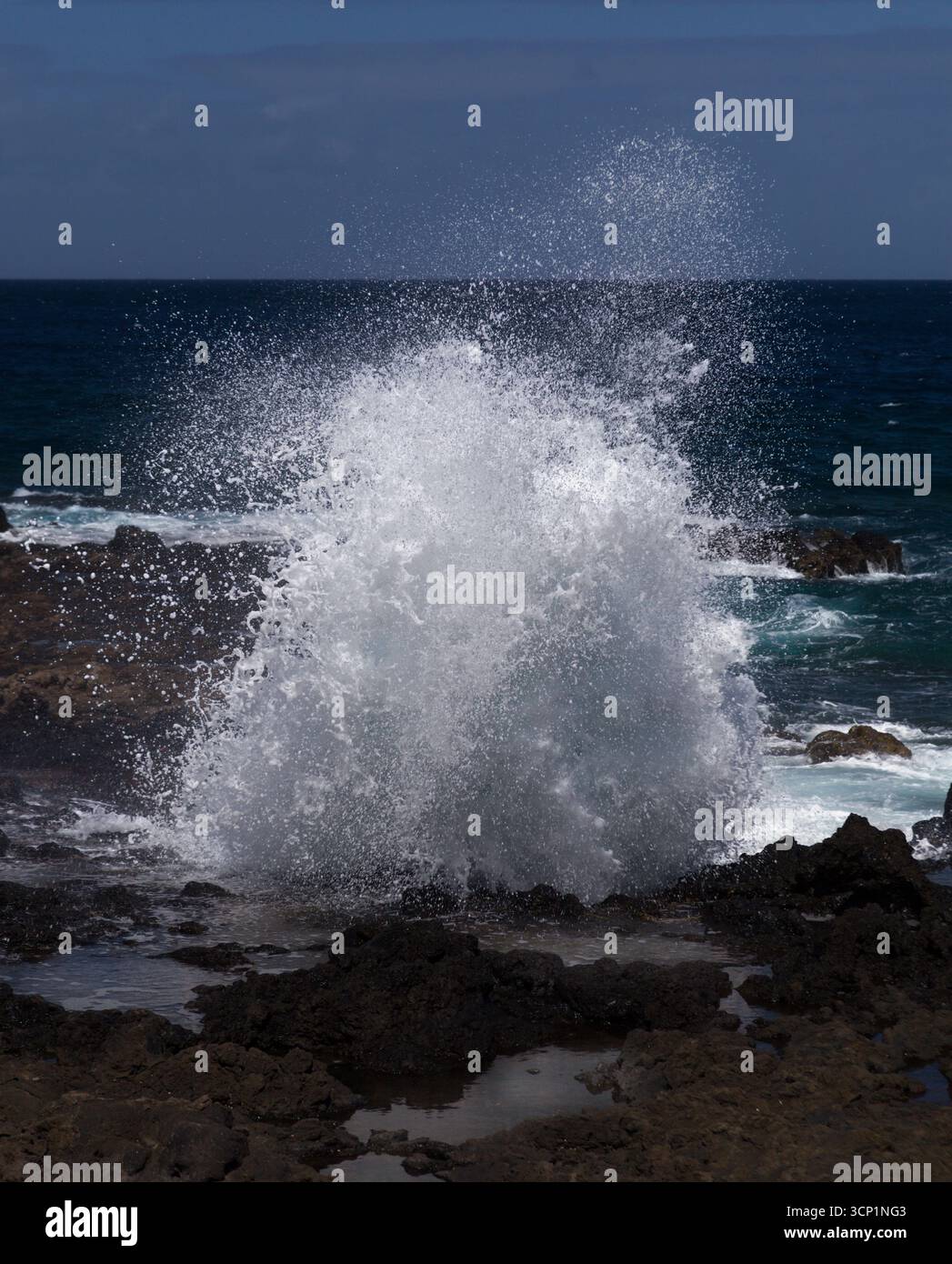 Gran Canaria, Nordwestküste rund um die natürlichen Schwimmbäder Salinas de Agaete, Wellen brechen gegen alte erodierte dunkle Lavaplattform Stockfoto