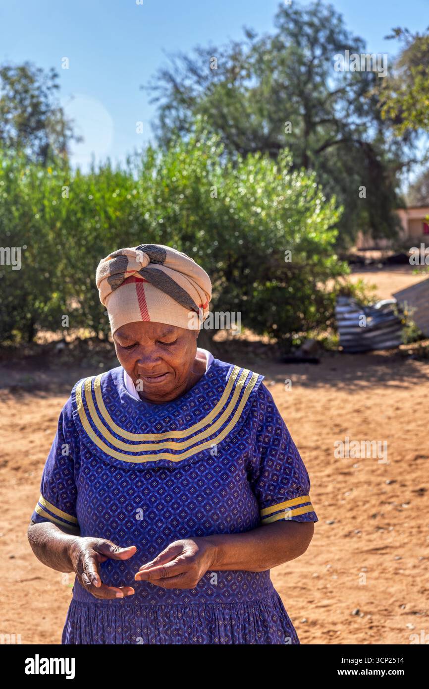 Afrika Dorf, alleinstehende ältere afrikanerin, draußen im Hof vor dem Haus, traditionelle Kleidung Stockfoto
