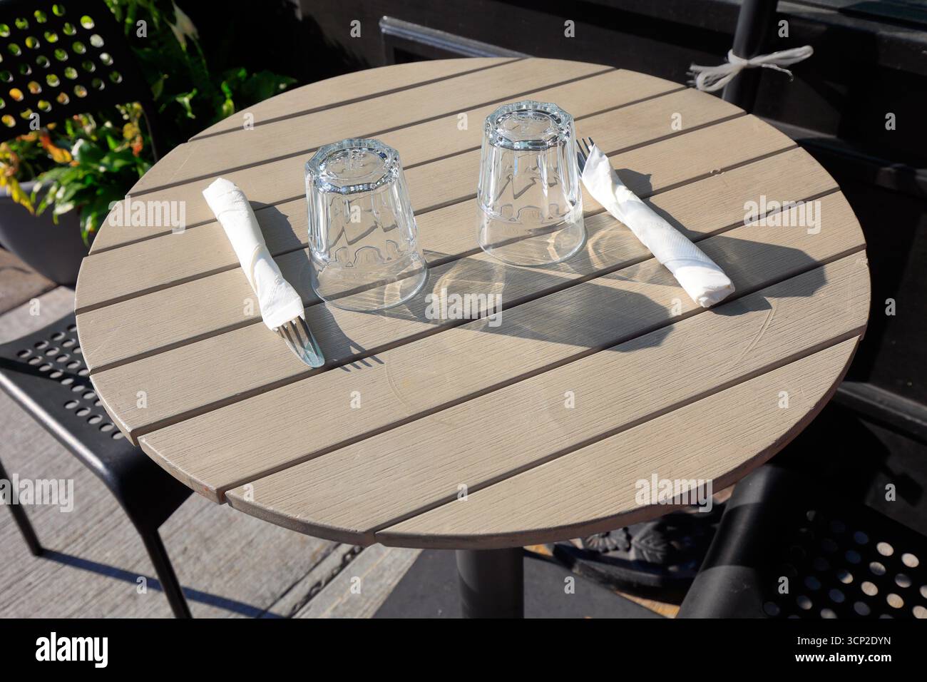 Ein einfacher Tisch, bestehend aus Wasserglas, Gabel und Messer auf einem Café-Tisch im Freien. Stockfoto