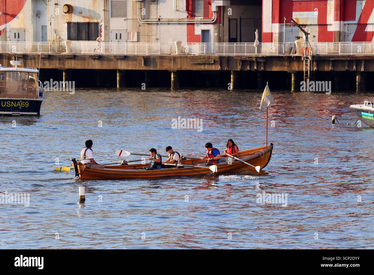 Asiatisch-amerikanische Teenager auf einem Village Community Boathouse mit 4 Personen Whitehall-Gig-Ruderboot auf dem Hudson River in der Nähe von Pier 40, New York City. Stockfoto