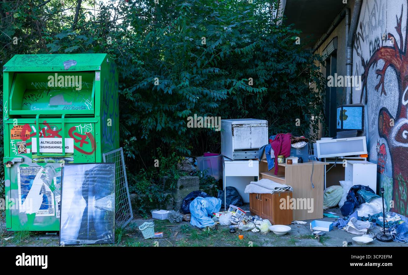 Hausmüll und Sperrmüll stapelten sich neben Spendenkisten in Berlin und symbolisieren Vernachlässigung und Verfall im öffentlichen Raum. Stockfoto