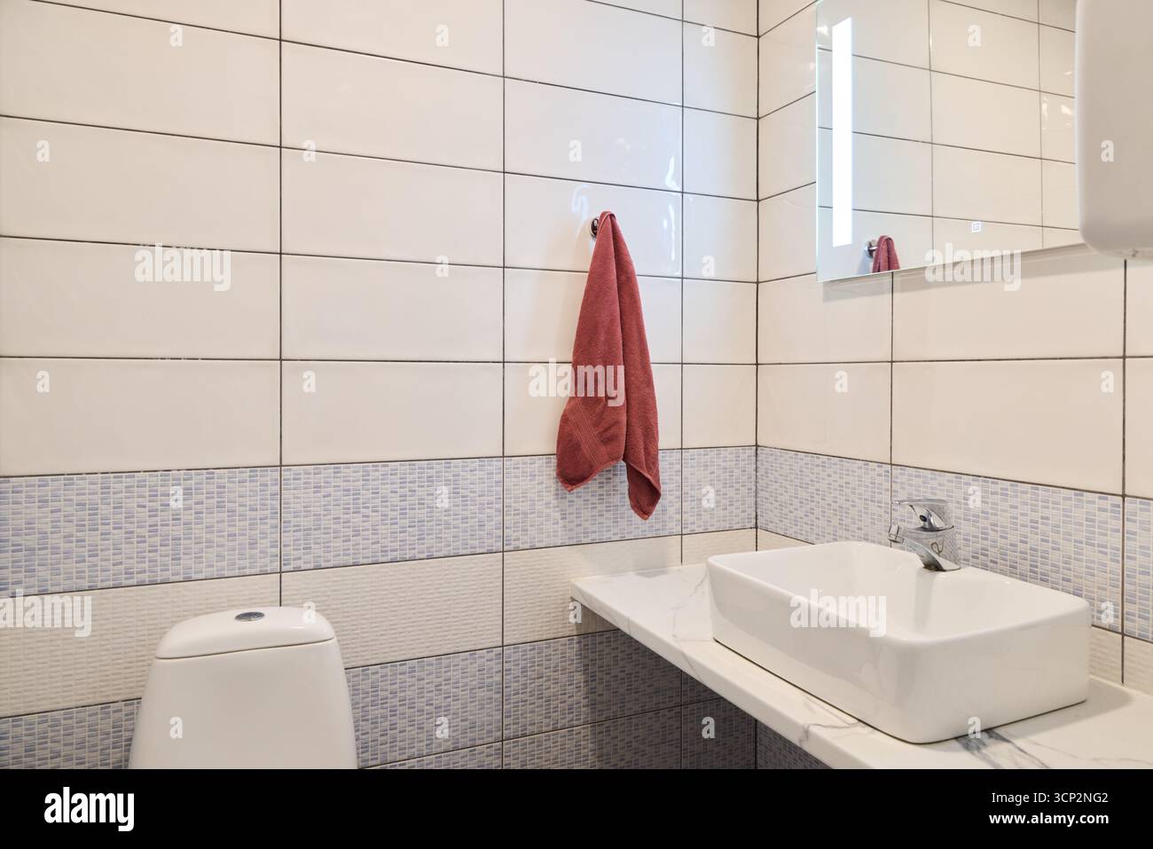 Das moderne Badezimmer verfügt über elegante weiße Fliesen und ein stilvolles Waschbecken Stockfoto