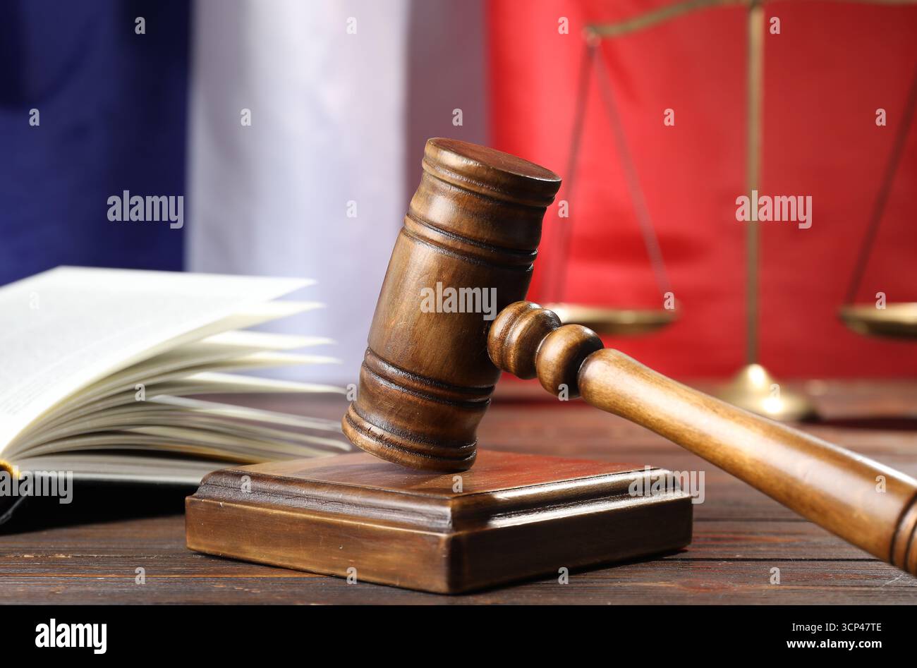 Hammer, Buch und Waage auf Holztisch vor der Flagge Frankreichs, Nahaufnahme Stockfoto
