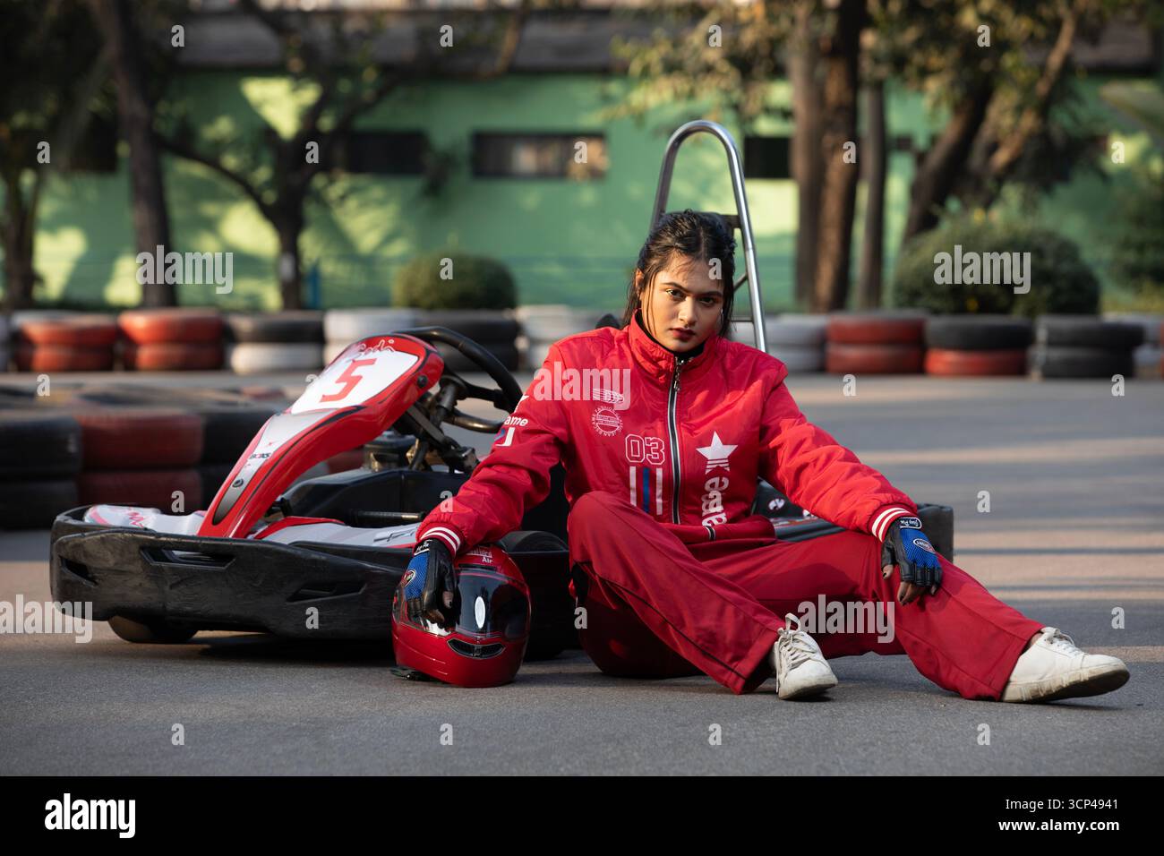 Selbstbewusste Frau im roten Trainingsanzug posiert mit einem Go-Kart Stockfoto