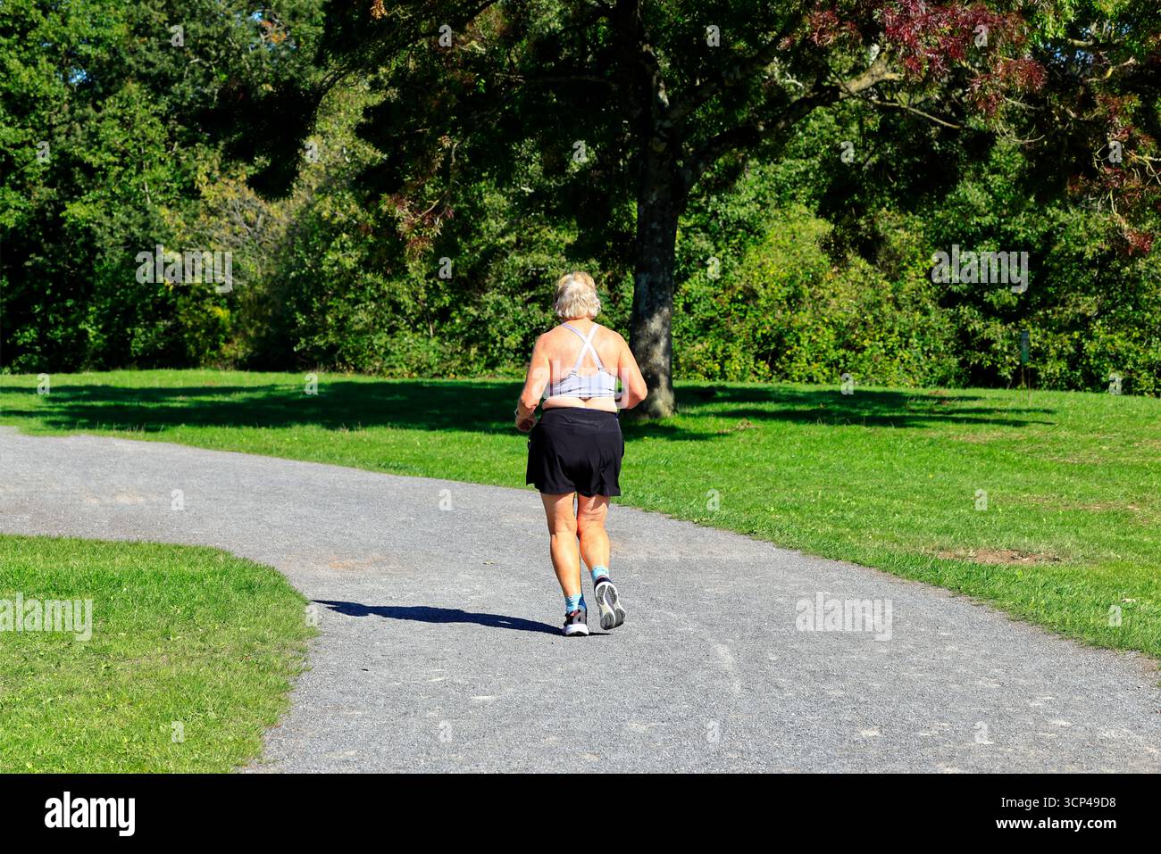 Ältere Frau, die auf einem Pfad läuft, Cosmeston Lakes und |Country Park, Penarth, South Wales. Vom September 2025 Stockfoto