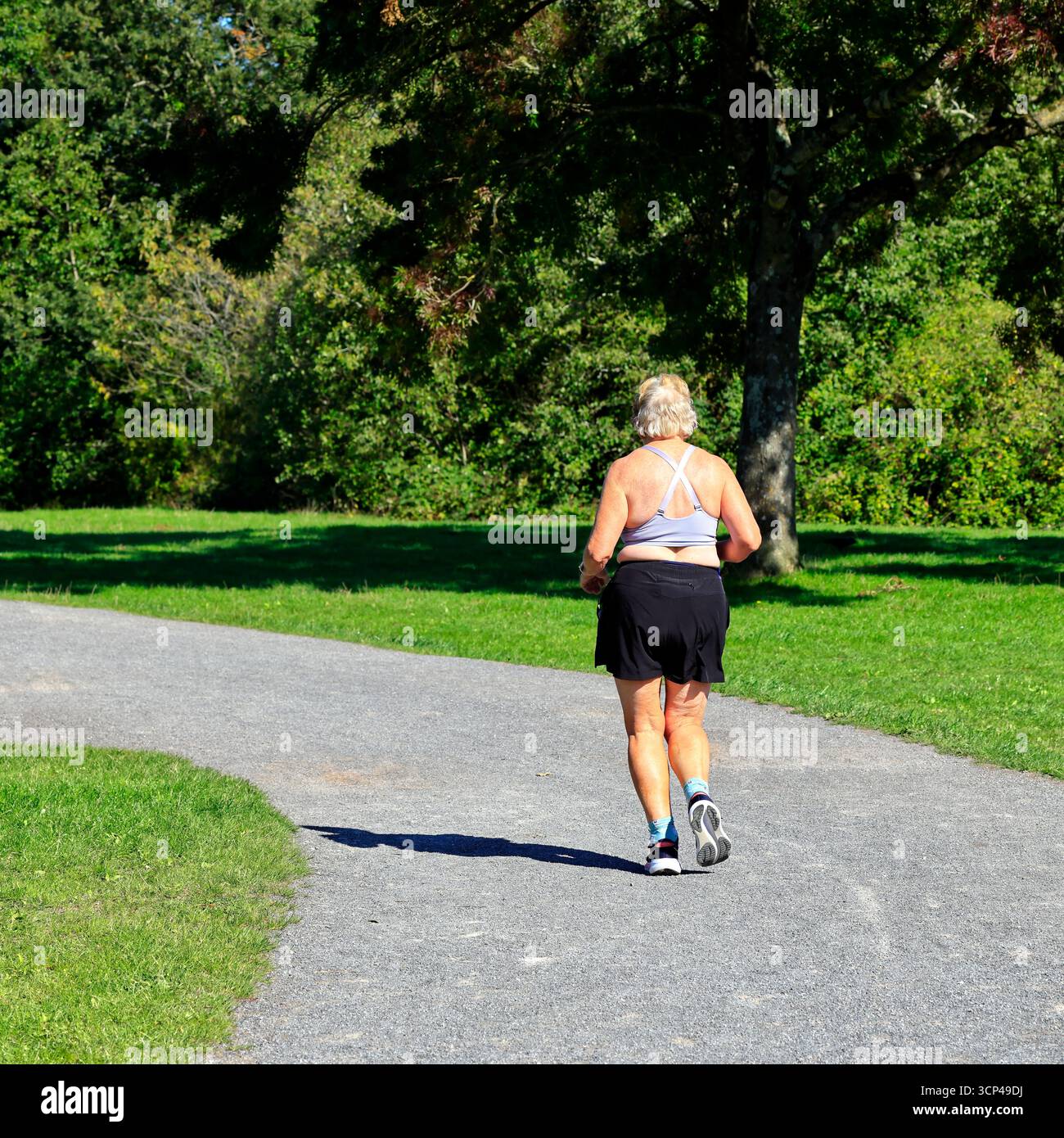 Ältere Frau, die auf einem Pfad läuft, Cosmeston Lakes und |Country Park, Penarth, South Wales. Vom September 2025 Stockfoto
