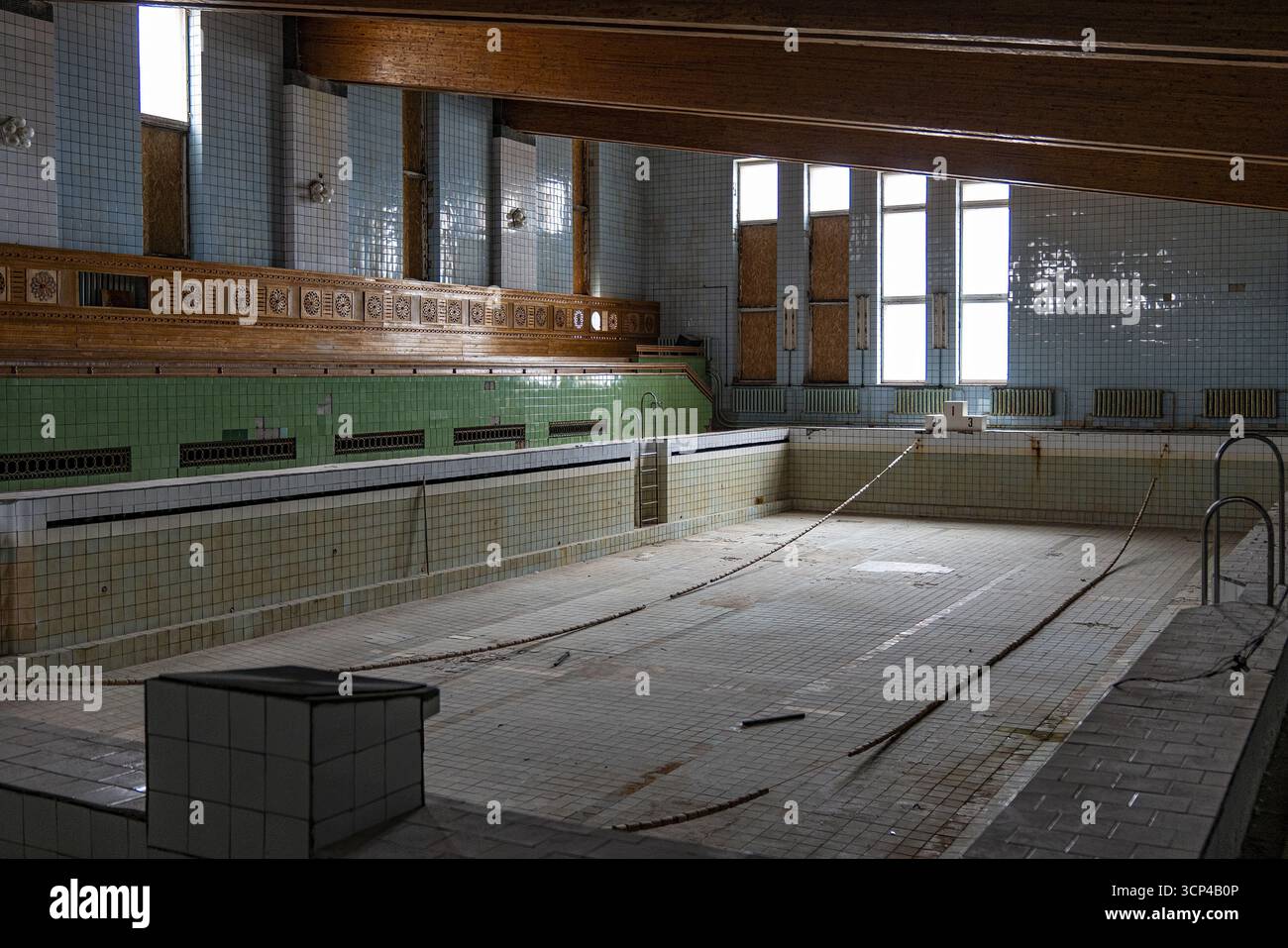 Blick auf einen abgeflachten Swimmingpool mit verblassten Fliesen und Holzakzenten, ein stiller Beweis für eine vergangene Ära in Pyramiden, Svalbard und Jan Mayen. Stockfoto