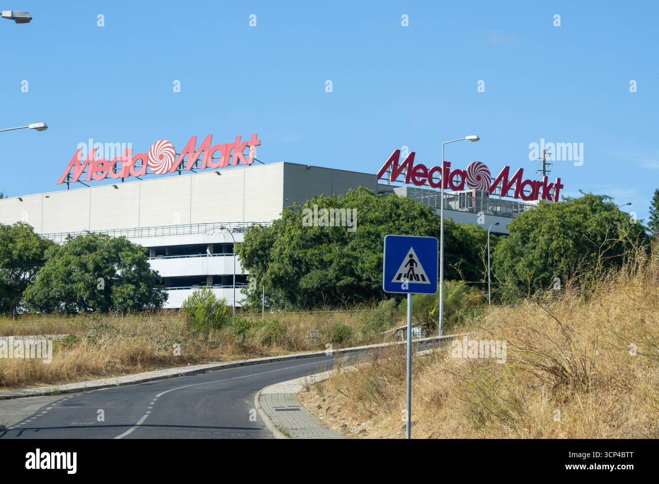 MediaMarkt, ein großer Einzelhändler für Unterhaltungselektronik, zeigt sein markantes rotes Logo auf seinem Geschäft in alfragide, portugal, mit einem Fußgängerschild im f Stockfoto