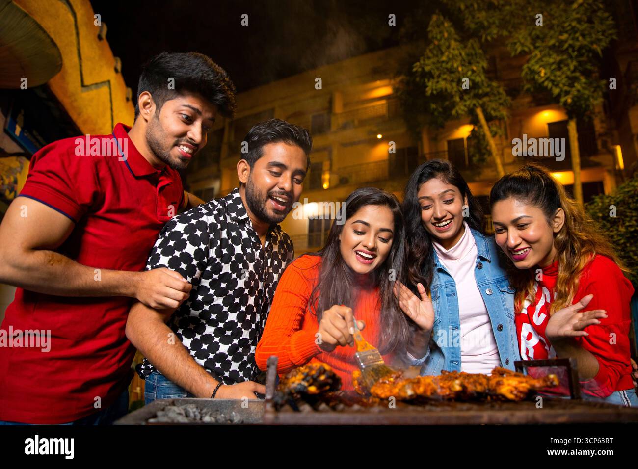 Glückliche Gruppe junger Freunde, die abends eine Barbecue-Party genießen Stockfoto