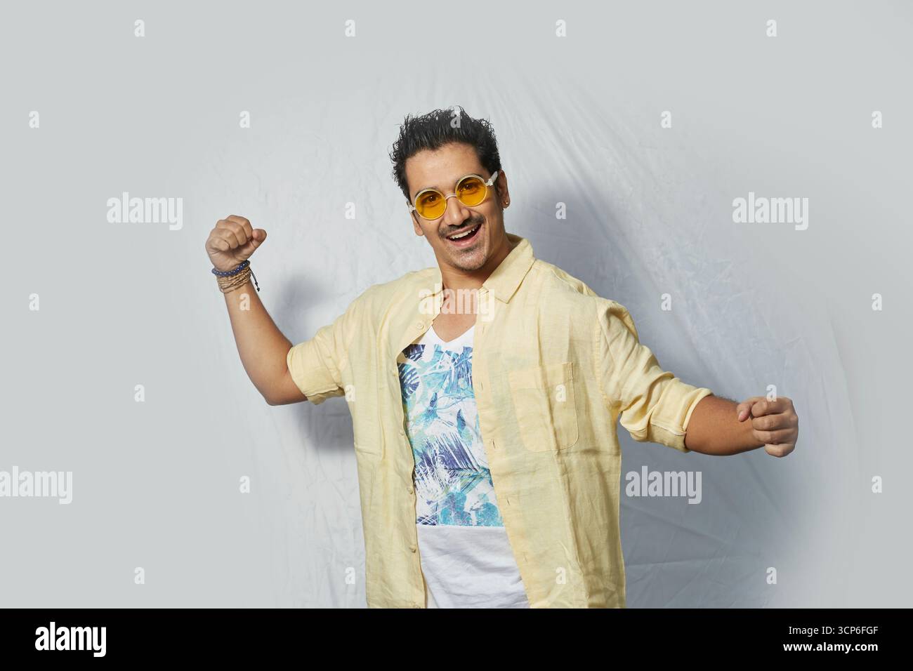 Aufgeregter und energiegeladener Mann in Sonnenbrille posiert mit einem fröhlichen Lächeln Stockfoto