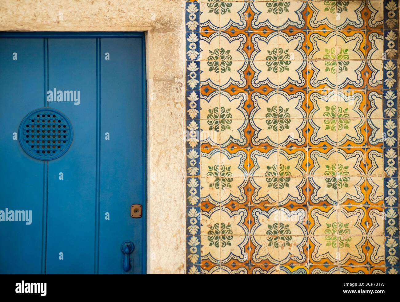 Ikonische blaue portugiesische Tür neben traditionellen Azulejo-Fliesen. Eine charmante und authentische Darstellung von Lissabons architektonischer Schönheit und kulturellem Erbe. Stockfoto