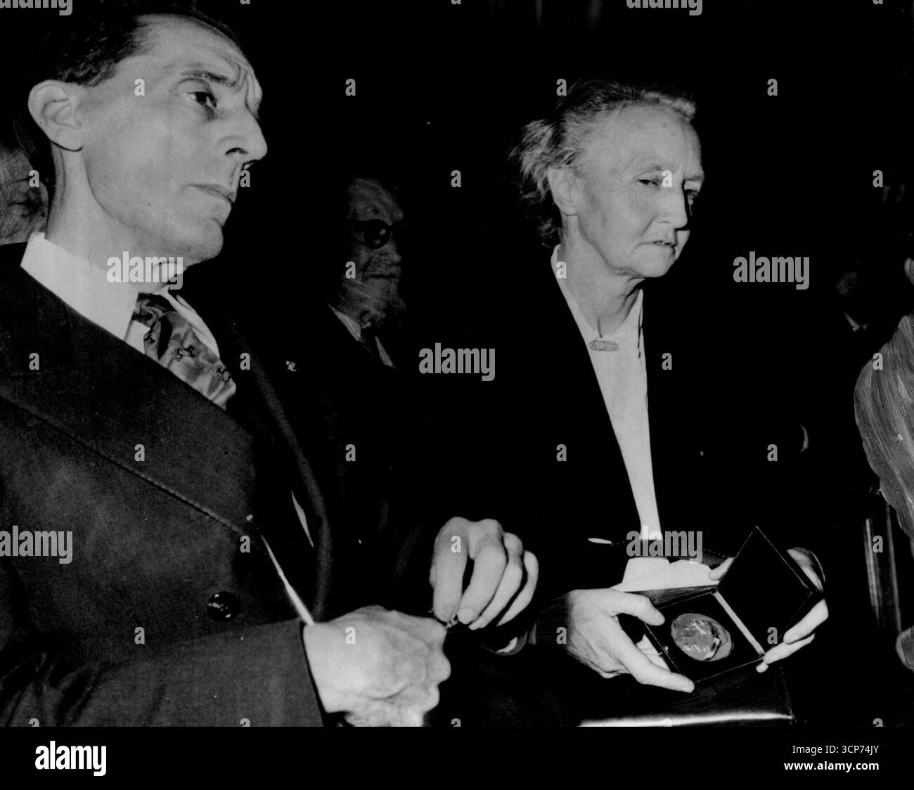 M. und Mme. Joliot-Curie geehrt - M. und Mme. Anlässlich des 20. Jahrestages der Entdeckung der künstlichen Radioaktivität wurde Frau Joliot-Curie (Tochter der berühmten Physikerin Mme Curie und M. Joliot-Curies) eine Goldmedaille verliehen. Die Zeremonie fand in der Sorbonne in Paris statt. Viele wissenschaftliche Experten waren anwesend, als Herr Maurice de Broglie im Namen seiner Akademie den Joliot-Curies vorstellte Joliot-Curie war französischer Atomchef bis 1950, als er wegen seiner kommunistischen Sympathien abgesetzt wurde. Oktober 1954. (Foto: Paul Po Stockfoto