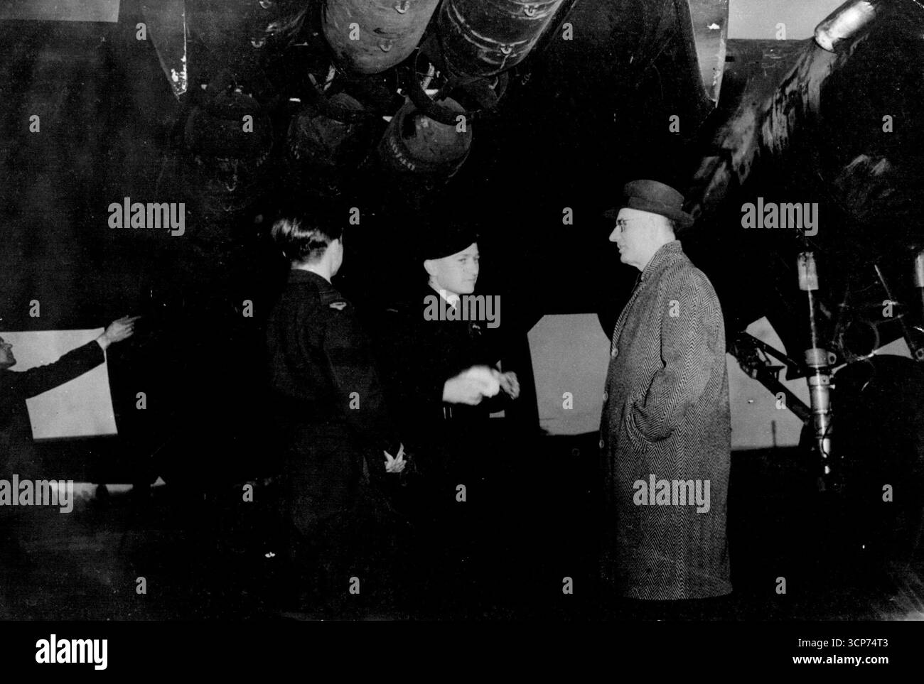 Mr. Curtin Sieht Australier Zu Raid Tours. Mr. Curtin steht unter der geladenen Bombenbucht eines Lancasters, kurz bevor es bei dem Angriff losging. Er spricht mit dem Anführer der Schwadron Rollo Kingsford-Smith, dem Neffen des verstorbenen Sir Charles Kingsford-Smith, dem berühmten Flieger Curtin, der australische Premierminister, besuchte eine Bomberstation und beobachtete, wie Männer der R.A.A.F. in ihrem Lancaster ausgingen, um Rangieranlagen in Tours, Frankreich, zu überfallen. Mai 1944. Stockfoto