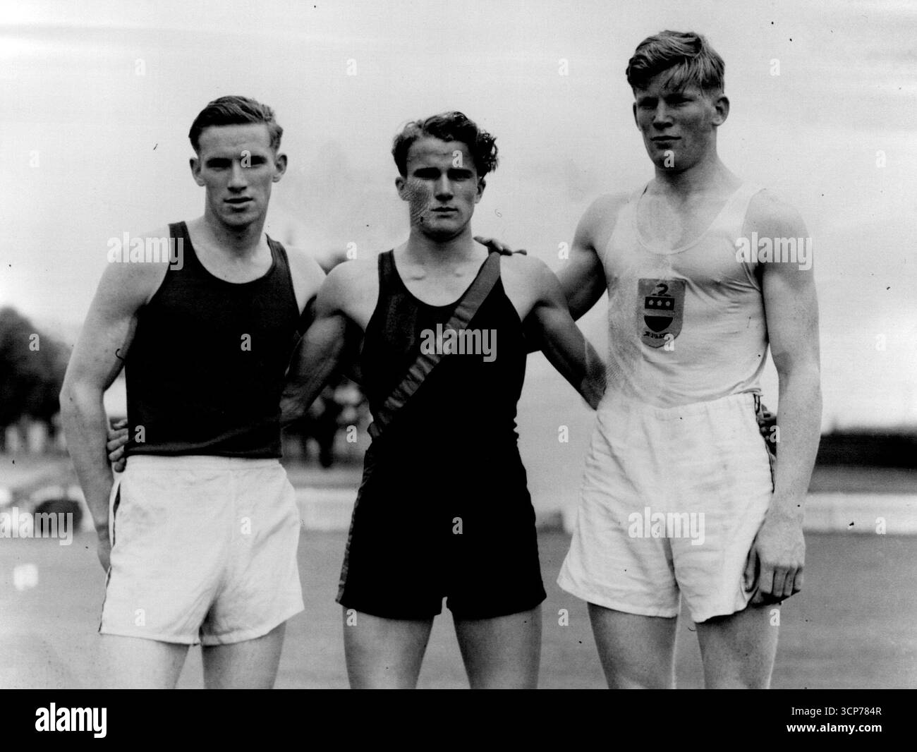 WA-Sprinter Bill de Grunchy (Mitte) mit D. Millar und D. Norman (rechts) der Guildford Grammar School bei 1947 Inter-School Sports, nachdem de Gruchy Open 100 Yd gewonnen hatte. Von Millar und Norman. September 1951. Stockfoto