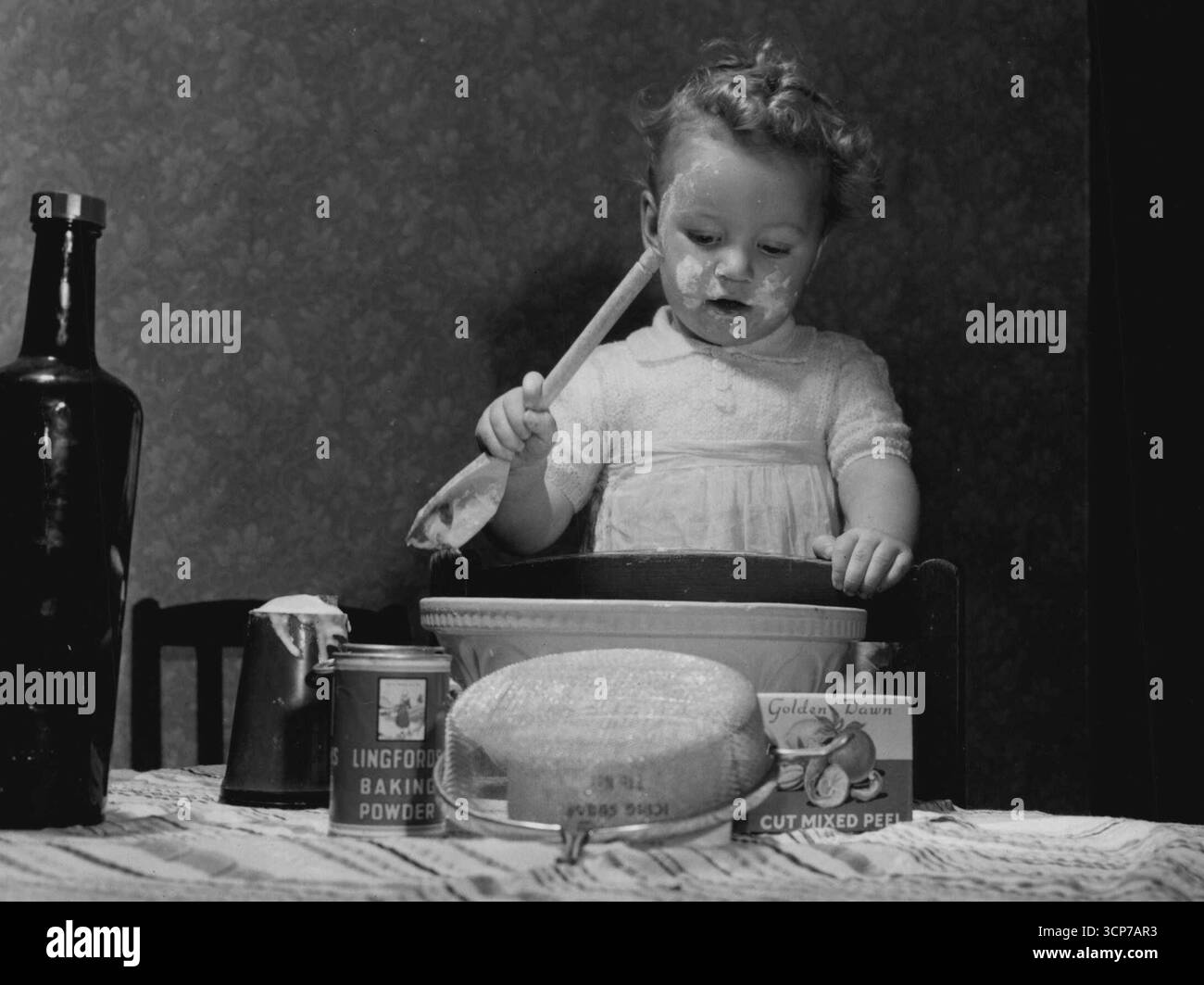 Ich bin Malcolm Oliver aus Newcastle-on-Tyne, England, und ich dachte, ich würde mit dem Weihnachtspudding helfen, während Mama nicht im Zimmer war. Es ist nicht so einfach, wie es scheint, obwohl es in der Tat eine tiefe Konzentration erfordert. Dezember 1954. (Foto von Daily Mirror). Stockfoto