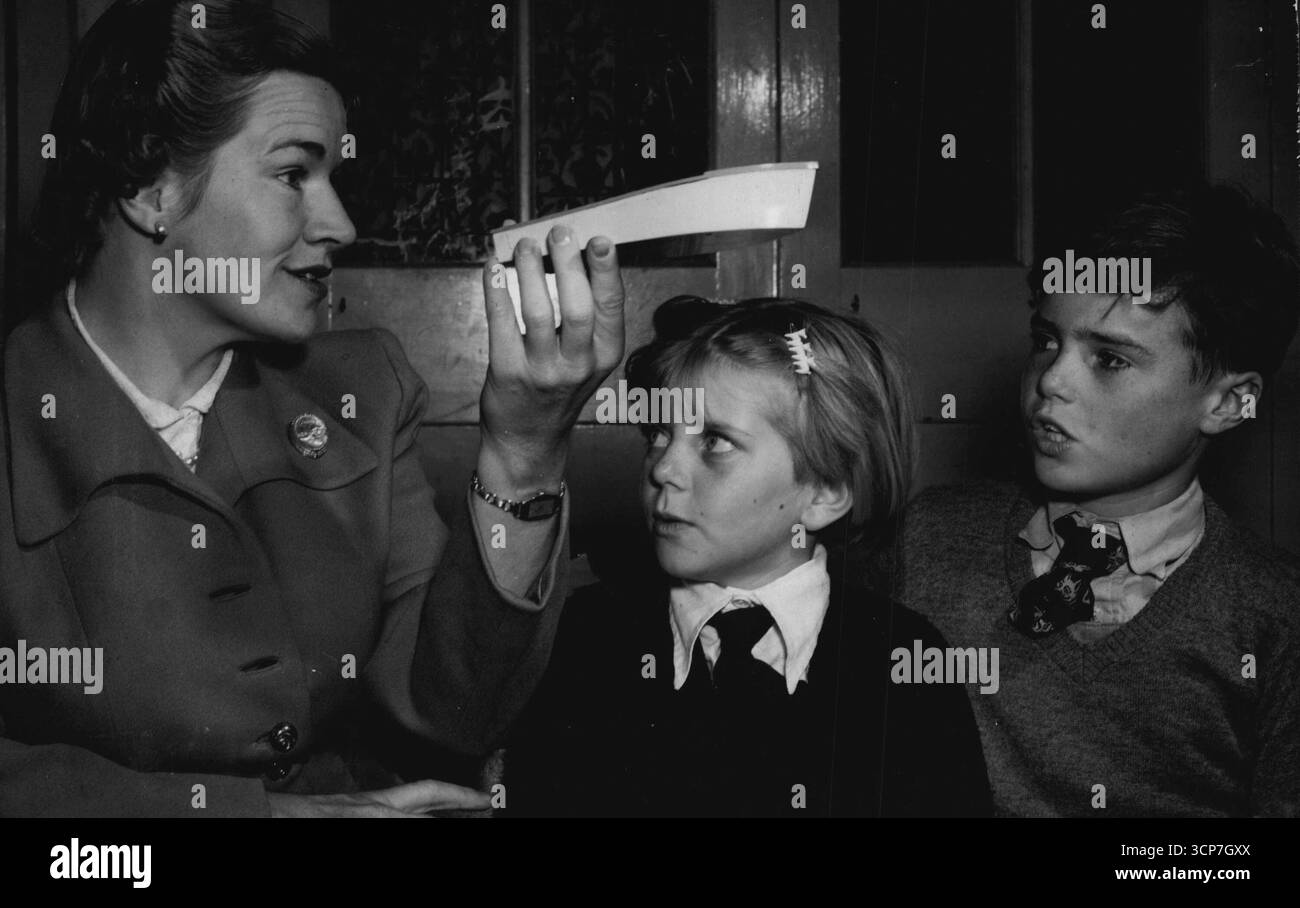 Miss Betty Shankland bläst auf Papier, um den Klang von 'F' zu illustrieren. Sie sind George Johnson und Graeme Nixon. Miss Shankland bläst auf Papier, um den Klang von 'F' für Georgina Johnson und Graeme Nixon zu illustrieren. März 1954. Stockfoto