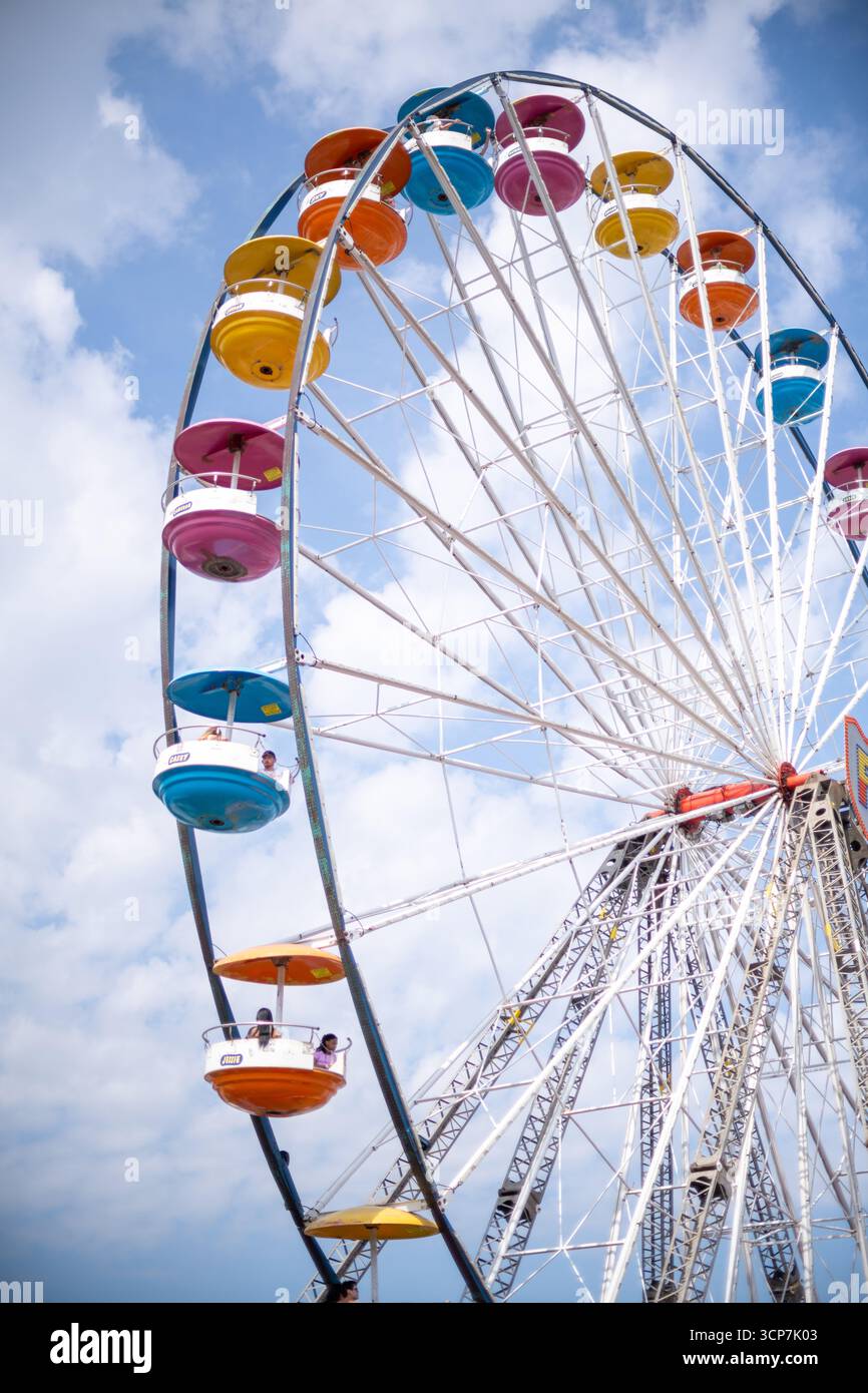FREDERICK Maryland // FREDERICK, Maryland — Ein Riesenrad mit bunten Gondeln wird auf der Great Frederick Fair in Frederick, Maryland, vor einem blauen Himmel mit verstreuten Wolken gesehen. Die Great Frederick Fair ist eine der ältesten Landwirtschaftsmessen in den Vereinigten Staaten und stammt aus dem Jahr 1854. Es zeigt landwirtschaftliche Ausstellungen, Viehwettbewerbe, Live-Unterhaltung und Karnevalfahrten. Die Messe findet in der Regel für zehn Tage Ende August und Anfang September statt und zieht Besucher aus der ganzen Region an. Stockfoto