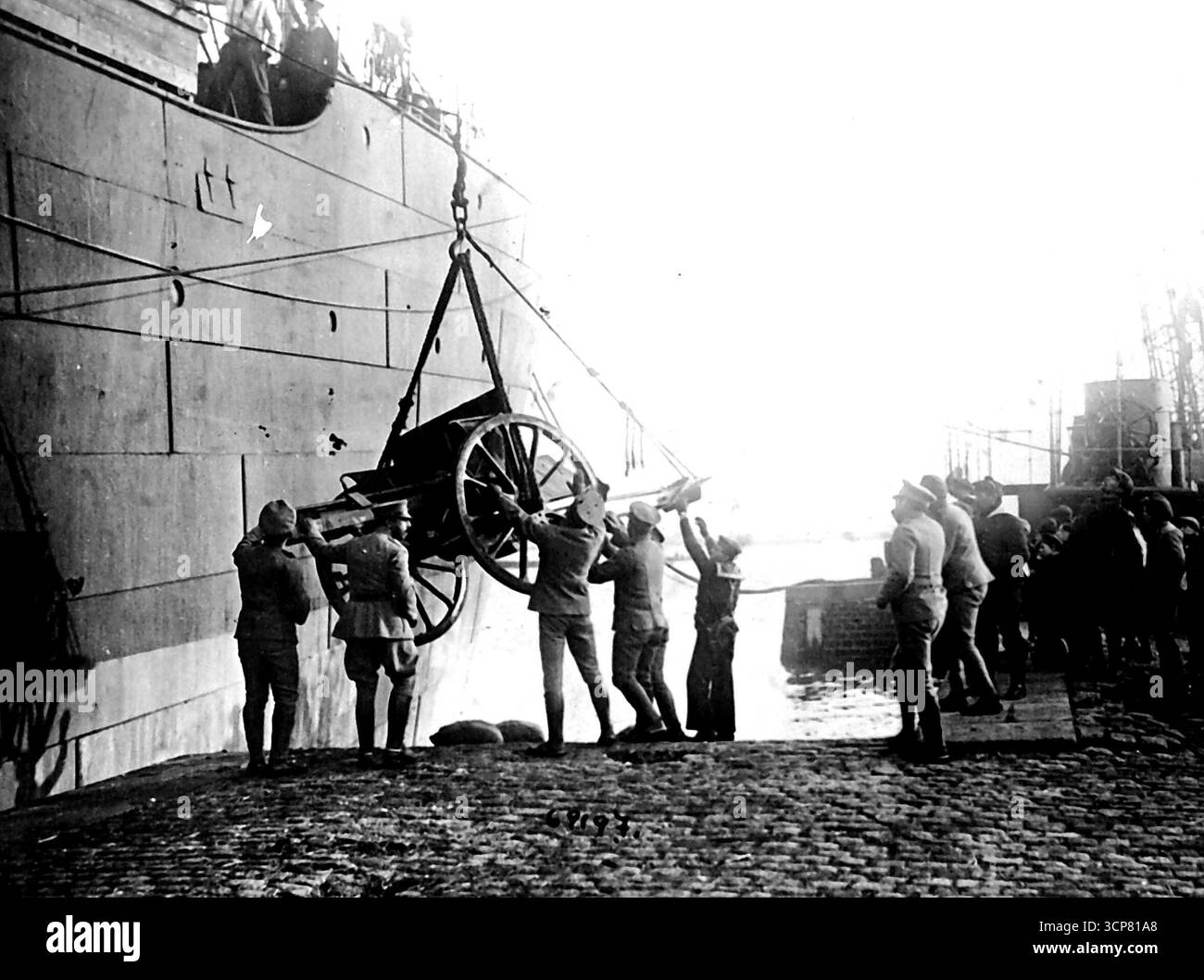 Portugiesische Truppen in Frankreich helfen den Hunnen zurück -- Obwohl die portugiesische Armee nichts zu sagen hat, hilft jedes bisschen im guten Stock. Portugiesische Soldaten werden hier gesehen, wie sie ihre Artillerie aus einem ihrer Transporte in einem berühmten französischen Hafen entladen. Juli. 1918. Stockfoto