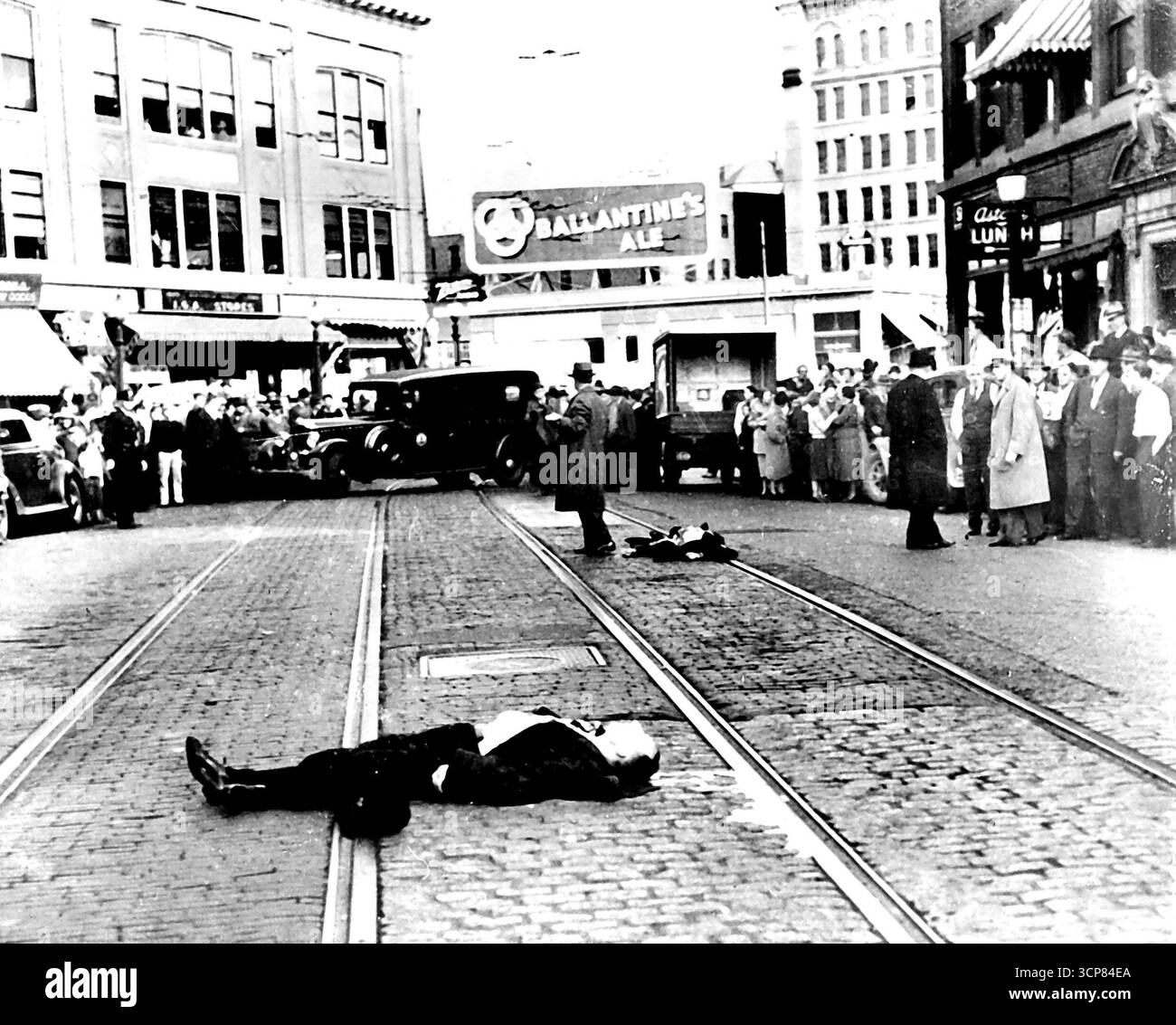 G-Men-Waffen töten bewaffnete Männer -- zwei Indiana-Gangster, Al Brady, 27 -- der aktuelle öffentliche Feind Nr. 1 des Mittleren Westens -- und sein Leutnant Clarence Lee Shaffer, Jr. 21, der von Bundesagenten für mehrere Morde und Dutzende von Banküberfällen gejagt worden war, wurden von G-Männern in einer wütenden Straßenschlacht in Bangor, Me, 12. Oktober getötet. Ein Komplize, James Dalhover, 30 von Madison, Ind., wurde gefangen genommen und G-man Walter Walsh, 28, aus Washington, wurde in der Schlacht verwundet. Hier ist der Tatort in der Main Street, Bangor, nach der Schlacht. Brady (Vordergrundstück) und Shaffer liegen tot über Trolleybahnen. Dezember 1937. (ACME). Stockfoto