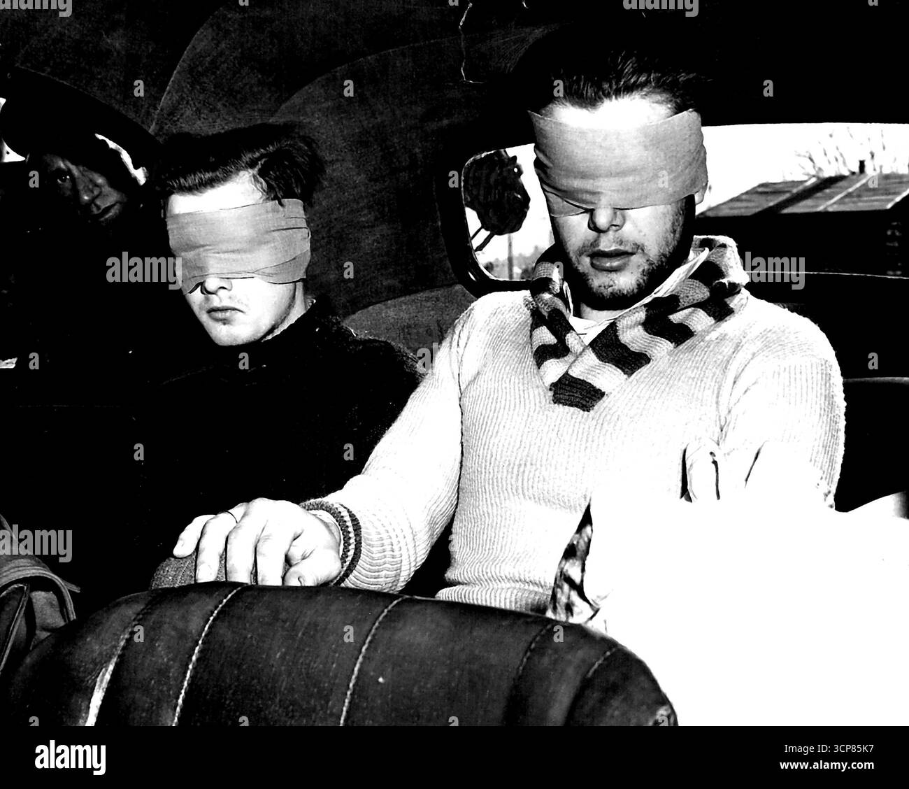 Kanadische Zerstörer versenken U-Boot -- zwei junge deutsche Gefangene werden in einem Auto gezeigt, das sie in ein Kriegsgefangenenlager brachte, nachdem sie von der kanadischen Fregatte "St. Catharines" gelandet waren. Hafenarbeiter sehen die Nazis durch das Autofenster, während sie blind gefaltet sitzen und ihre Sachen an ihrer Seite haben. Sie wurden gerettet, nachdem sie das U-Boot verlassen hatten, das schließlich mit einem Ring kanadischer Kriegsschiffe und dem Zerstörer ICARUS der Royal Navy sank. 30. Juni 1944. (Foto: Kanadier W.I.B). Stockfoto