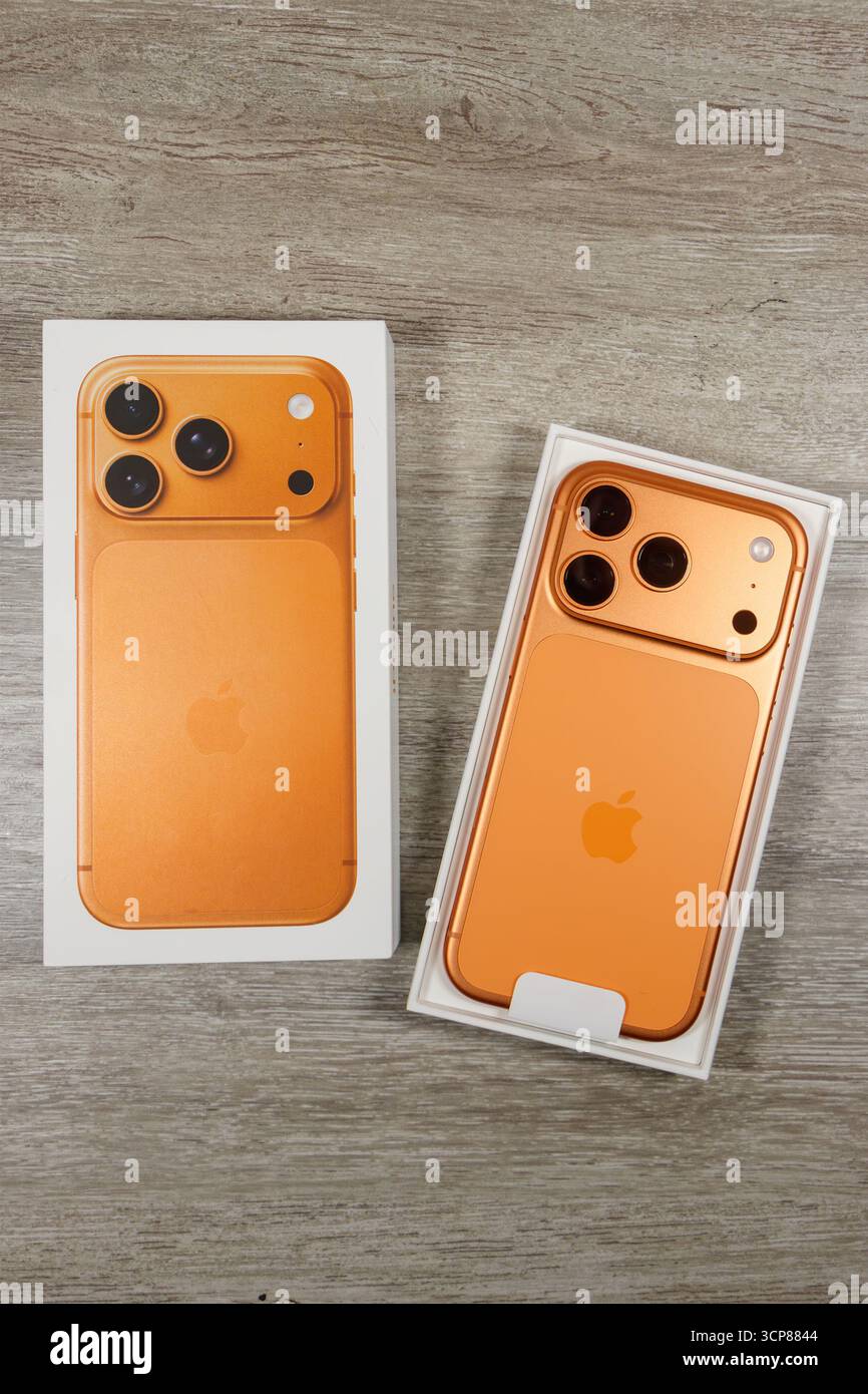 Orange iPhone 17 Pro mit der Box auf einer Holzoberfläche, die die Rückseite und das Kameradesign des Smartphones zeigt Stockfoto