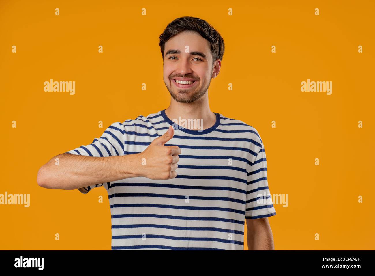 Gutaussehender Mann mit Handzeichen, Daumen hoch Geste. Happy Young Guy auf Gelb Stockfoto