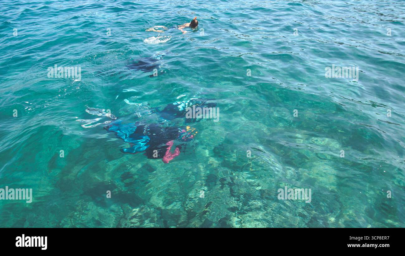 Blick auf die Wasseroberfläche mit Tauchern, die direkt unter der Wasseroberfläche sichtbar sind und sich darauf vorbereiten, hervorzutreten Stockfoto