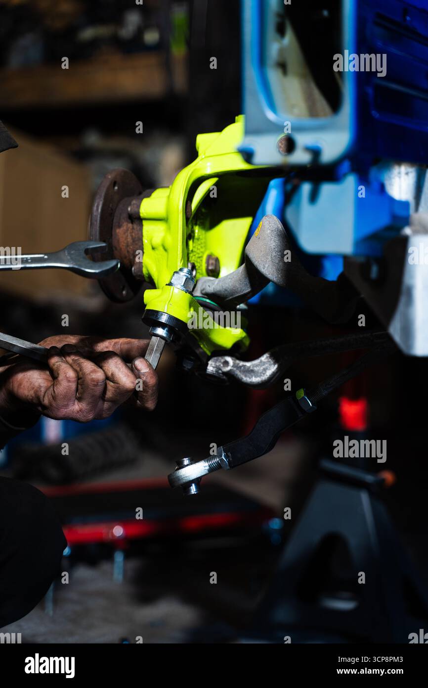 Einbau der Performance-Federung und Bremsscheibe für Drift-Kontrolle und Bremsen. Einbau der Rennscheibenbremse mit leuchtend grünem Achsschenkel an der Aufhängung. Stockfoto