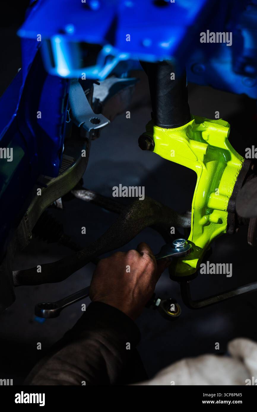 Einbau der Rennscheibenbremse mit leuchtend grünem Achsschenkel an der Aufhängung. Einbau der Vorderradaufhängung und der Bremsscheibe. Einbau der Performance-Federung Stockfoto