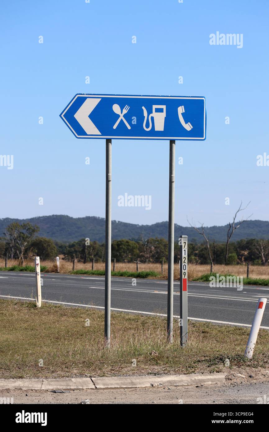 Blauer Rastplatz mit Schild für Lebensmittel und Benzin neben einer Straße in einer ländlichen Gegend Stockfoto