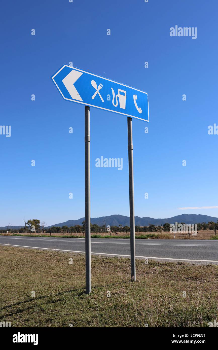 Blaues Straßenschild für einen Rastplatz mit Einrichtungen für Lebensmittel und Benzin vor blauem Himmel Stockfoto