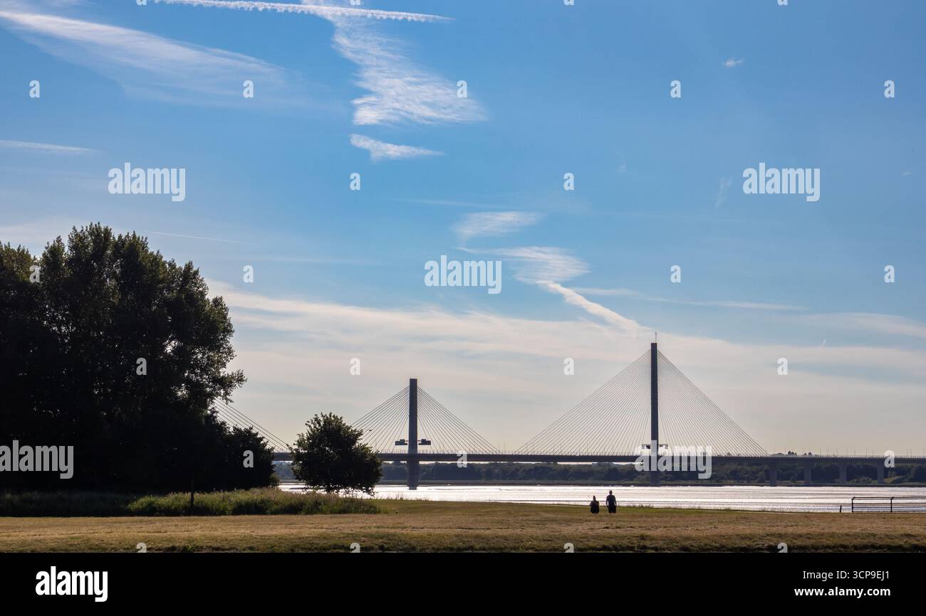 Die Mersey Gateway Bridge, die den Mersey überspannt und von Spike Island in Widnes an einem klaren Tag aus gesehen wird, wo Menschen im Vordergrund laufen Stockfoto