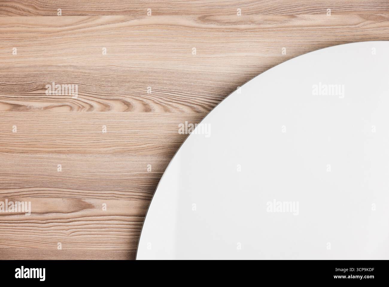 Ein sauberer, weißer Spiegel liegt auf einer warmen Holzwand, die natürliche Kornmuster hervorhebt. Abstrakte, moderne Innenausstattung Stockfoto