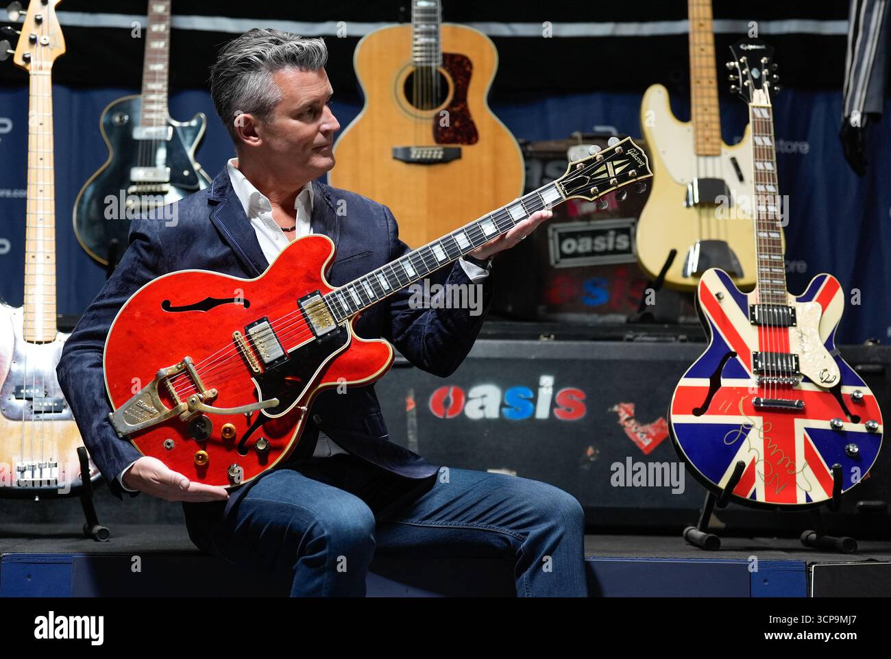 Stephen Lane, CEO von Propstore, hält Noel Gallaghers 1960 kirschrote Gibson es-355-Gitarre, die in Paris von Liam Gallagher am Abend des Aufbruchs der Oasis beschädigt wurde und seither repariert wurde, mit einer Schätzung von £ 250.000 bis £ 500.000, während einer Vorschau für die bevorstehende Auktion für Musik-Erinnerungsstücke, die vom 23. Bis 24. Oktober in London stattfindet. Bilddatum: Dienstag, 16. September 2025. Stockfoto