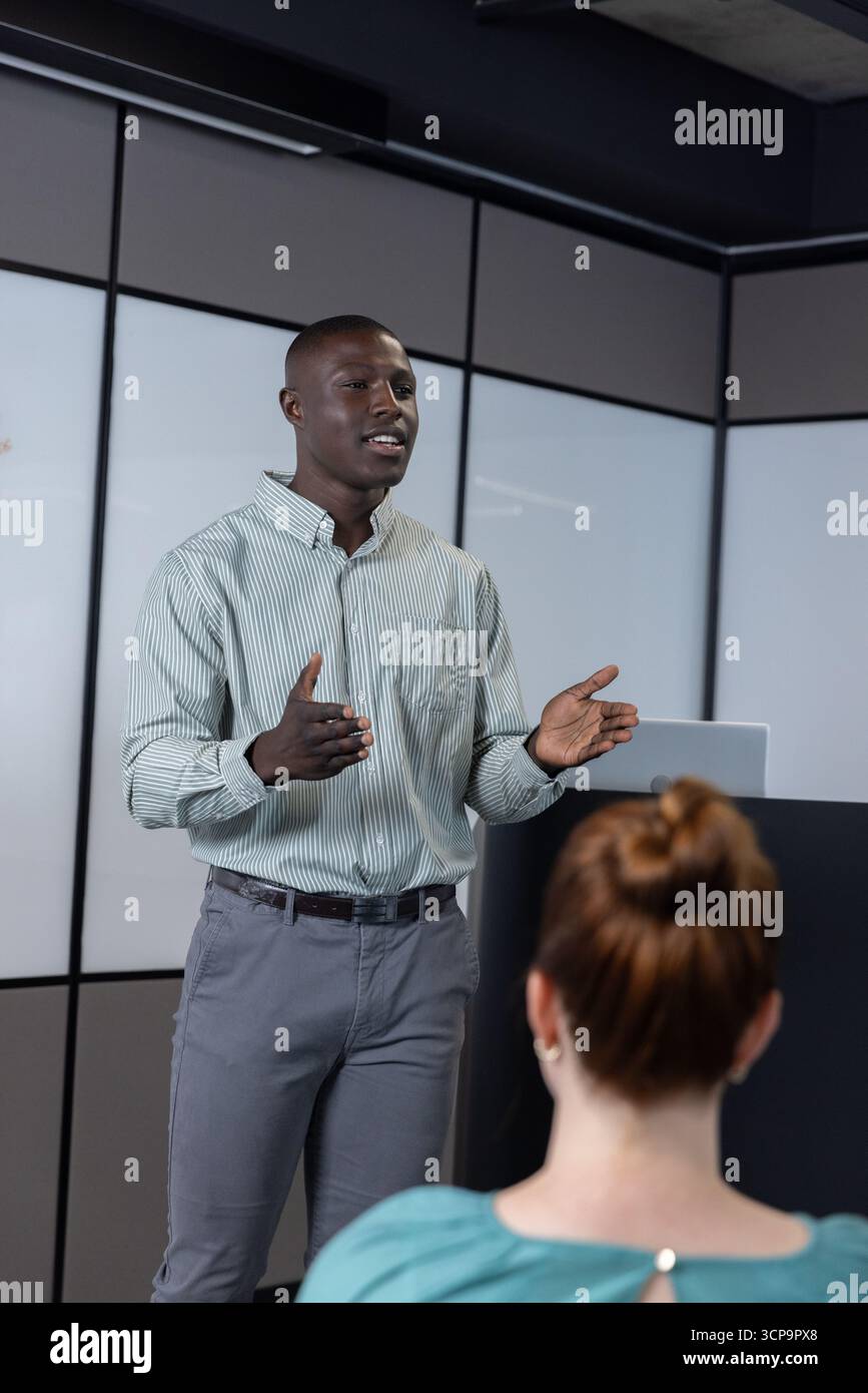 Verschiedene Kollegen hören zu, Moderator auf dem Podium mit Gesten im Konferenzraum mit Laptop Stockfoto