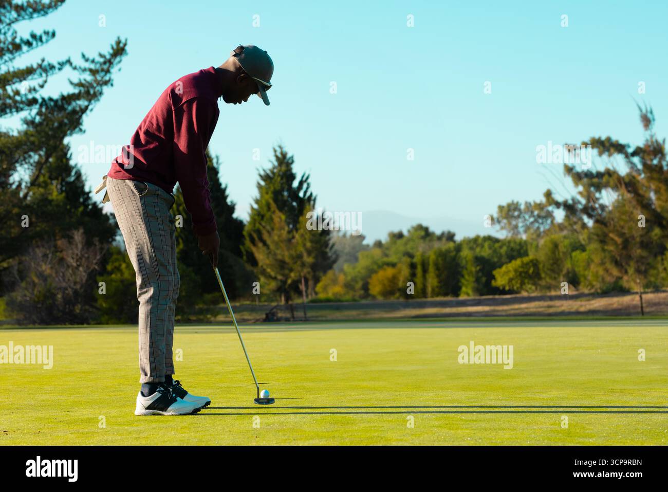 Afroamerikaner, der Putt auf Grün hält, Putter und Ball, Kopierraum Stockfoto