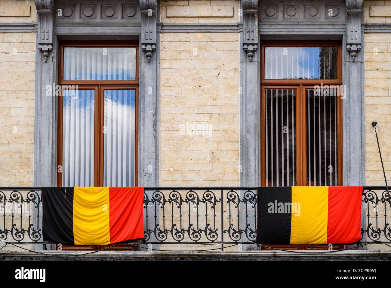 Belgische Fahnen hängen über dem Geländer des dekorativen Eisenbalkons in Brüssel, der Hauptstadt Belgiens Stockfoto