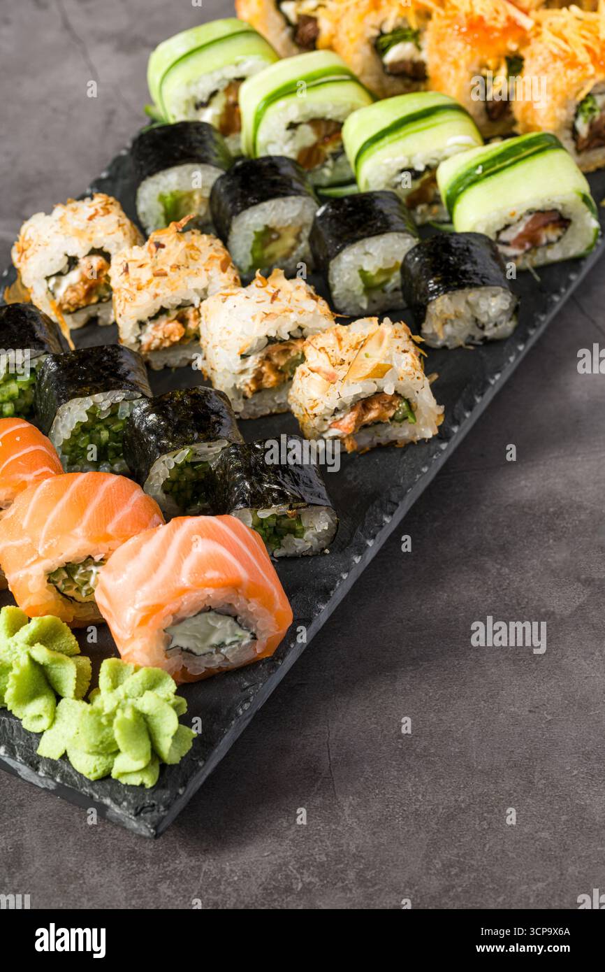 Verschiedene Sushi-Brötchen serviert auf einem Schieferteller mit Wasabi, Sojasauce und Ingwer Stockfoto