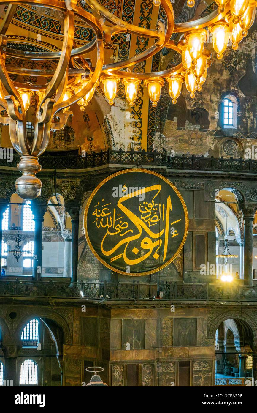 Osmanischer Kronleuchter Und Arabische Kalligrafiemedaillons In Der Hagia Sophia Istanbul. Byzantinische Architektur, Islamische Kunst, Goldene Beleuchtung, Historische Stockfoto