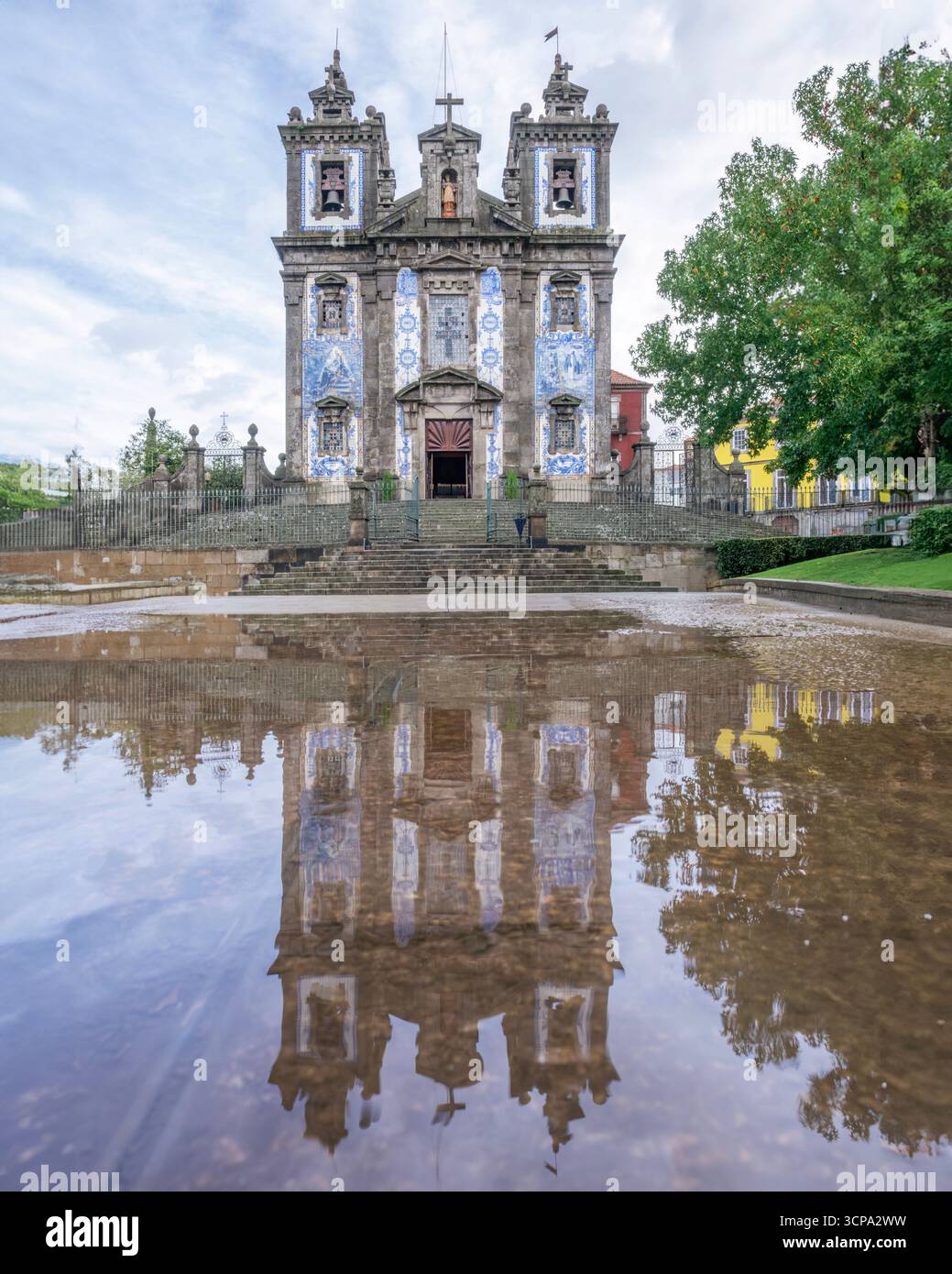 Igreja De Santo Ildefonso Mit Perfekter Reflexion In Großer Puddle Nach Regen. Barocke Kirchenfassade mit blauen Azulejo-Fliesen, historisches Zentrum von Porto Stockfoto