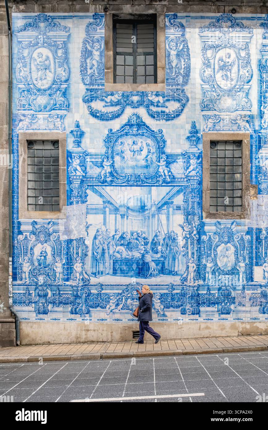 Frau Mittleren Alters, Die An Der Herrlichen Azulejo-Mauer Von Igreja Santo Ildefonso Vorbeiläuft. Portugiesische Keramikkunst, Straßenszene des kulturellen Erbes von Porto Stockfoto