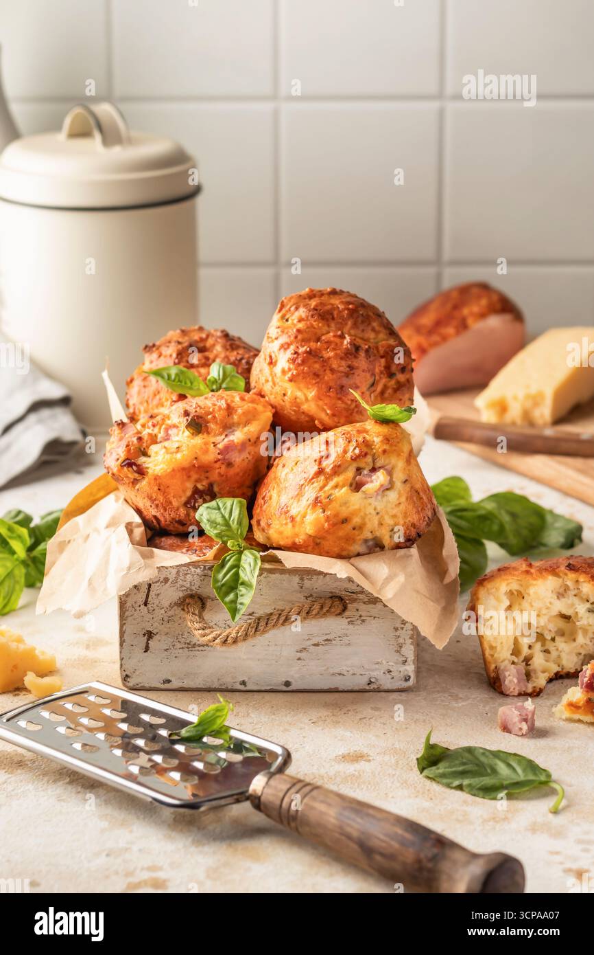 Herzhafte Eiermuffins mit bazil, Schinken und Käse in weißer Holzkiste auf Küchentischhintergrund. Gesundes und schnelles Frühstück am Morgen. Vertikal Stockfoto