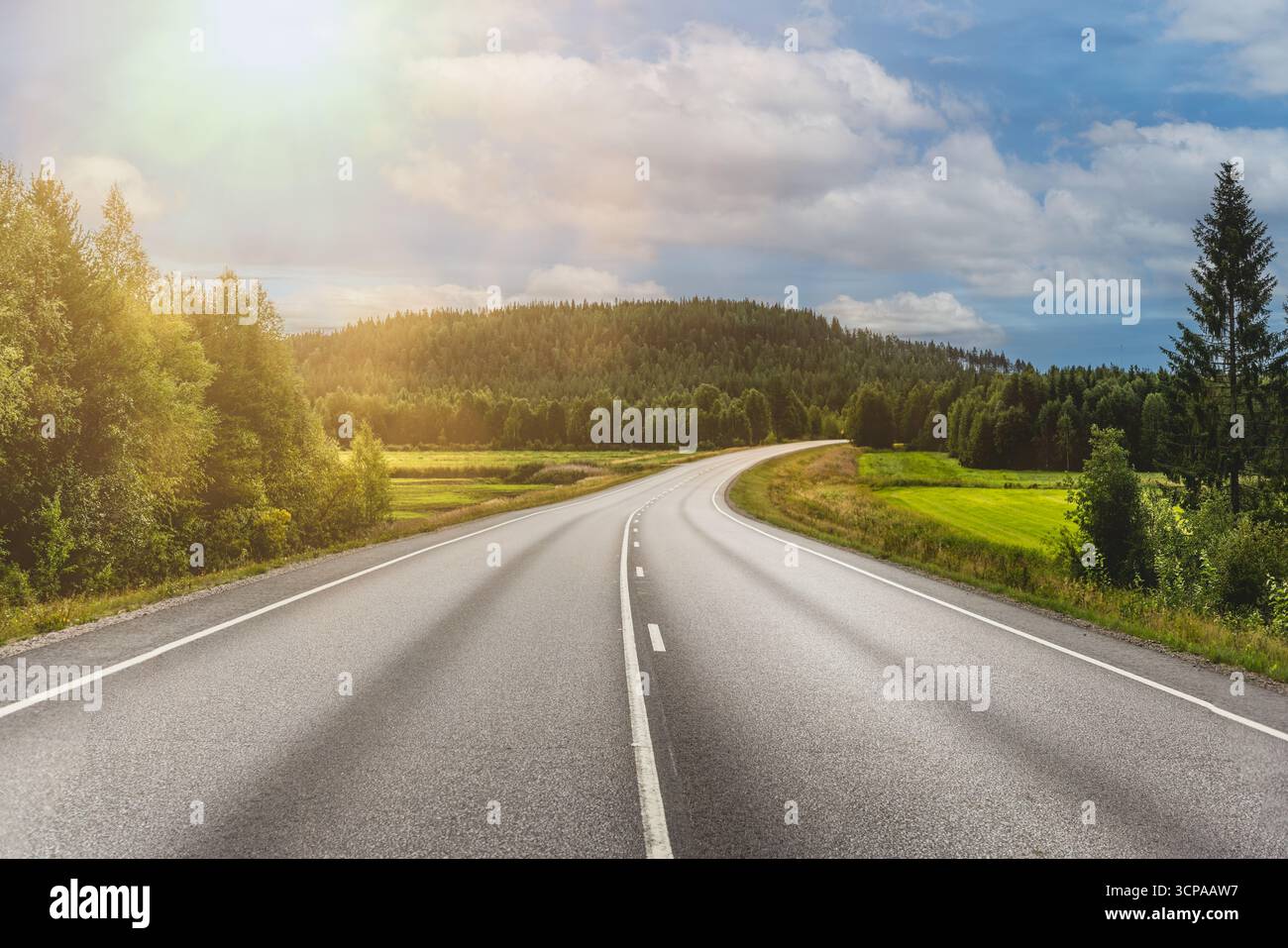 Kurvige Straße durch die malerische Landschaft Finnlands Stockfoto