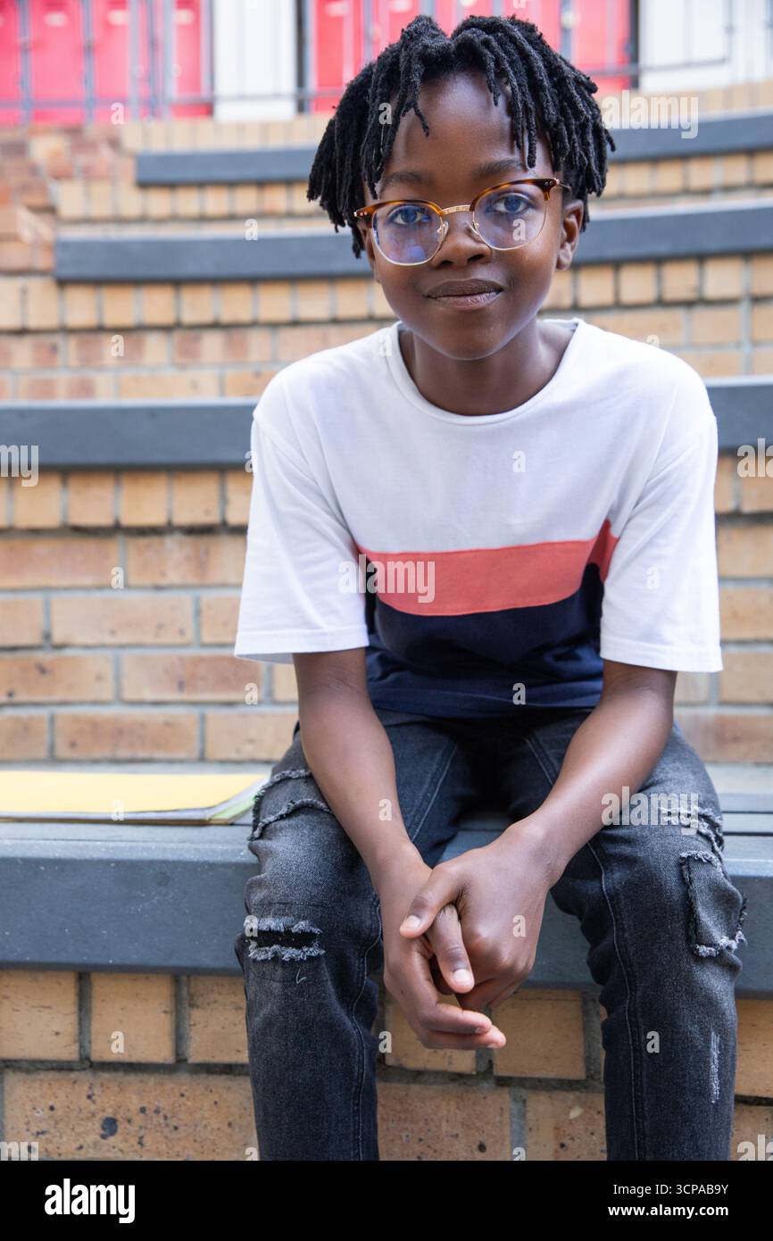 afroamerikaner sitzt draußen auf Betontreppe mit Brille Stockfoto