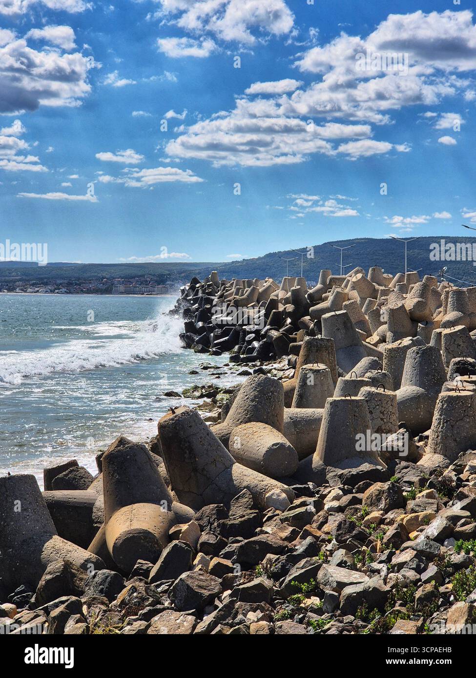 Stürmisches Meer in der Nähe des Wellenbrechers. Wellenbrecher aus Beton-Tetrapoden. Küste mit großen Betonbrechern, die die Küste vor Wellen schützen. - Smartphone-aufgenommenes Stockfoto