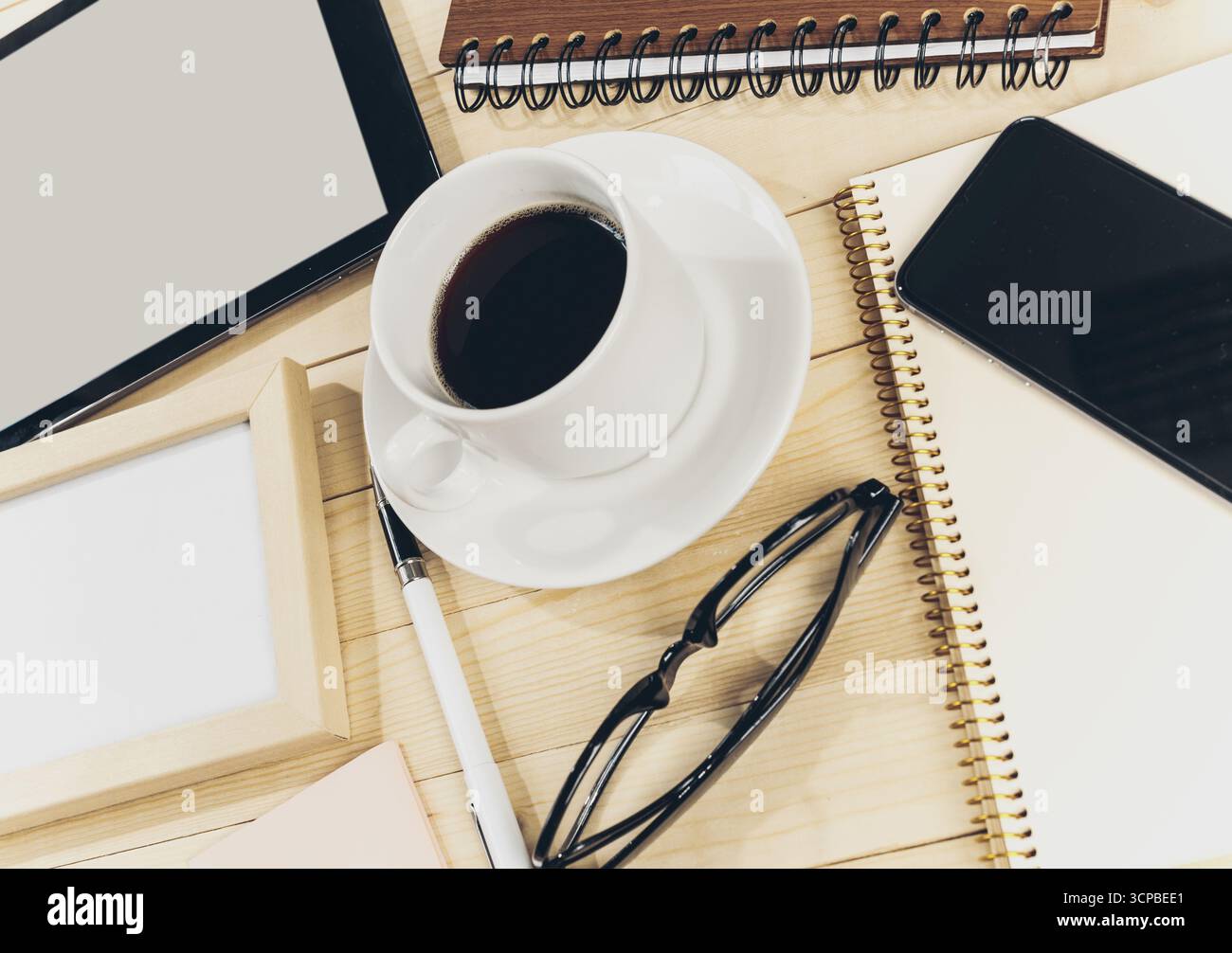 Kaffee und Notizbücher auf einem Holztisch während einer Arbeitssitzung Stockfoto