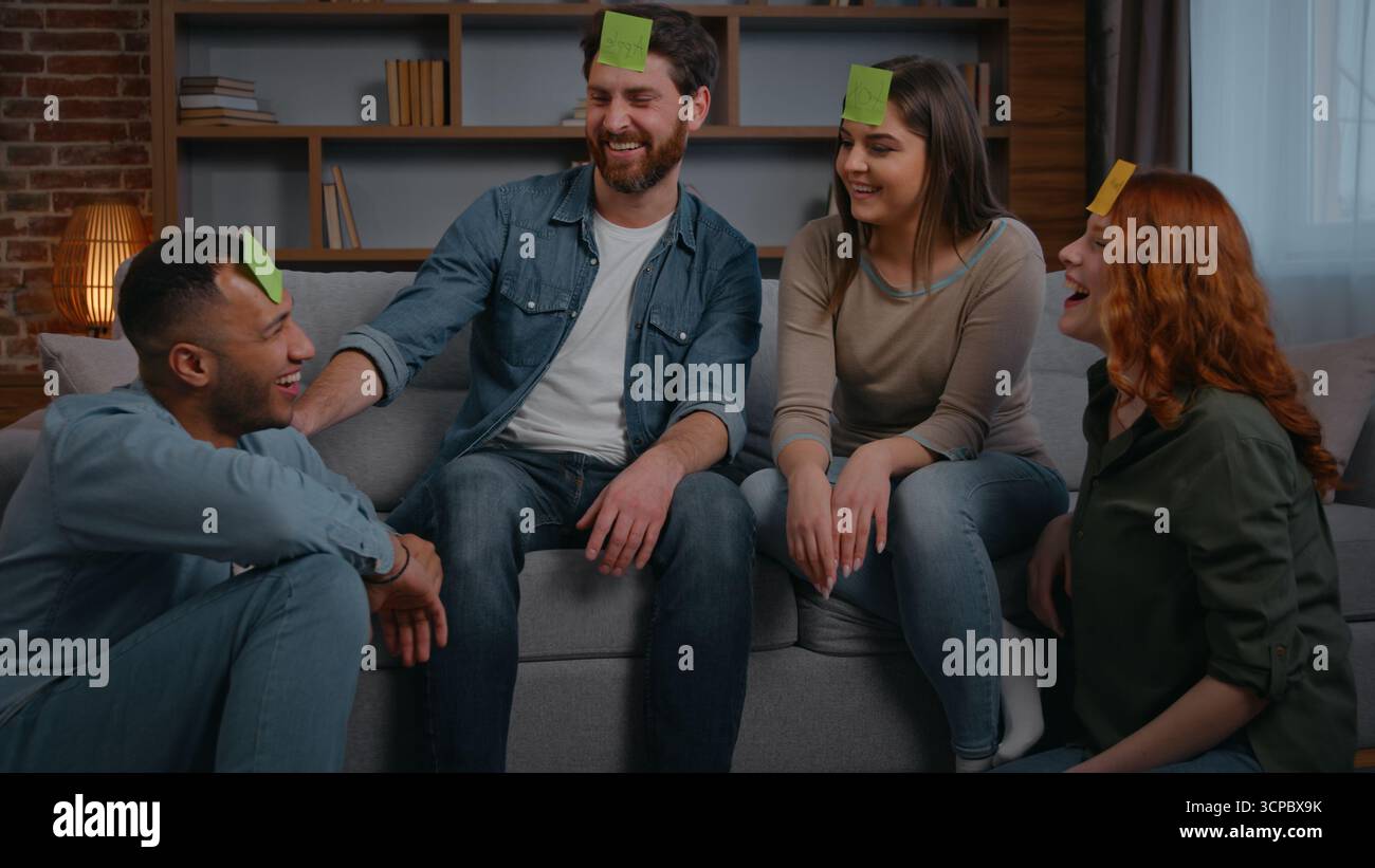 Gruppe von multirassischen Freunden, die zu Hause Charaden spielen, Wochenendspaß reden, fragen, Wortnamen raten, Glückliche multinationale Männer, Frauen spielen Stockfoto
