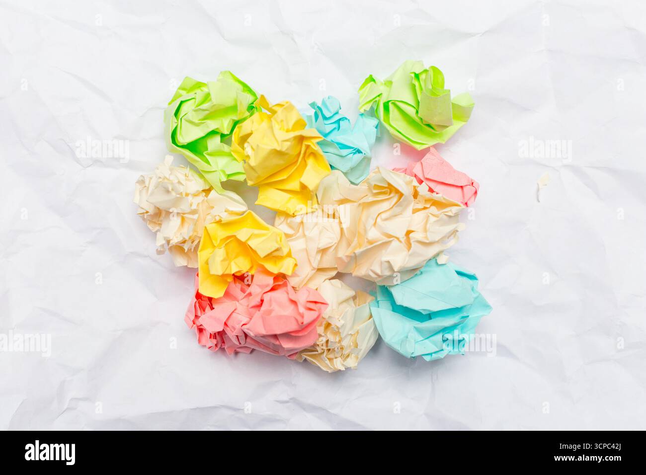 Bunte, zerknitterte Papierstücke auf weißem Hintergrund in einem Kunstprojekt verstreut Stockfoto