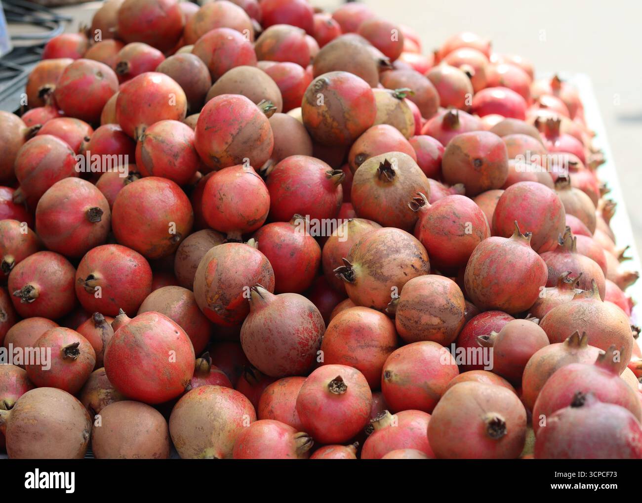 Frische reife Granatäpfel, die auf einem lokalen Obstmarkt zum Verkauf angeboten werden. Stockfoto