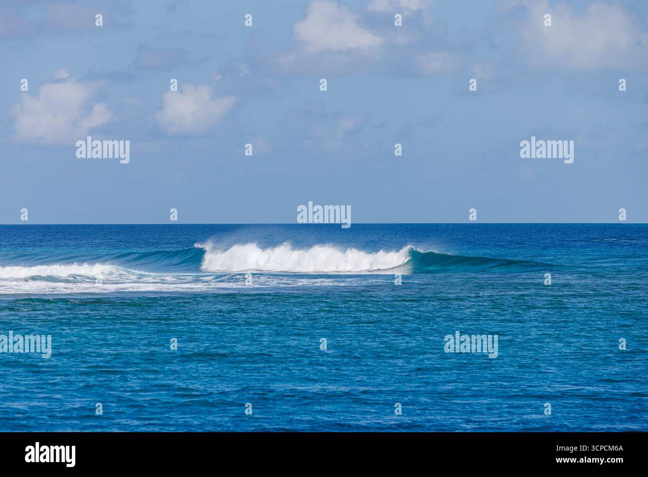 Wunderschöne blaue Ozeanwellen krachen und plätschern am Horizont unter sonnigen Wolken. Kraftvoller, dynamischer Hintergrund für den Sommer im Hintergrund für Reisen Stockfoto
